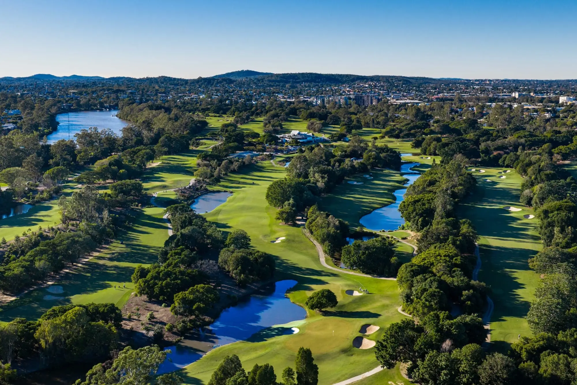 Aerial of fairways, lakes and city skyline at sunset