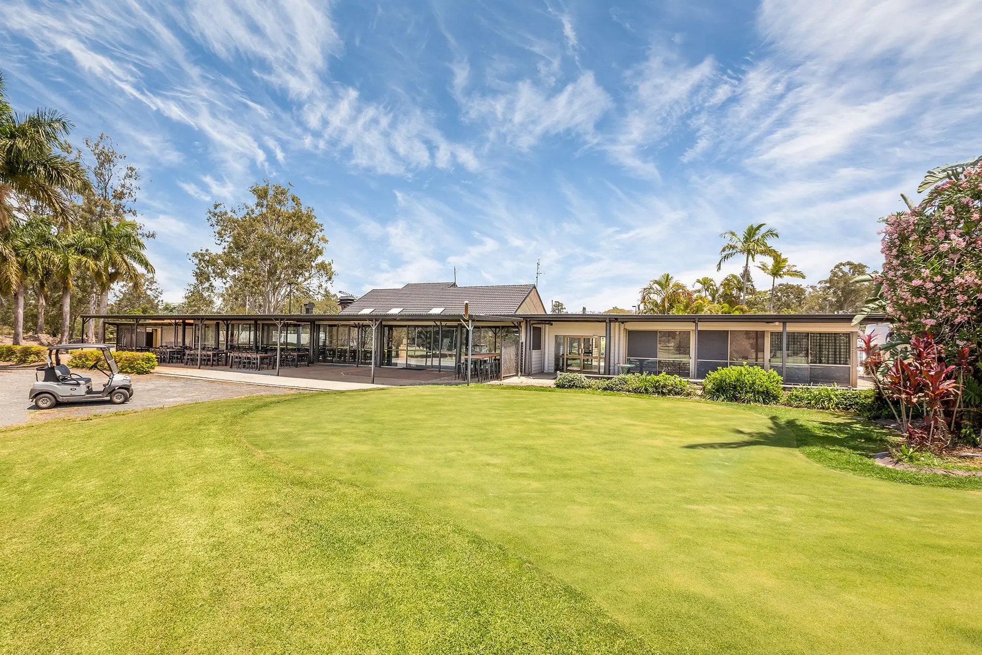 Low clubhouse and palms behind a mown lawn