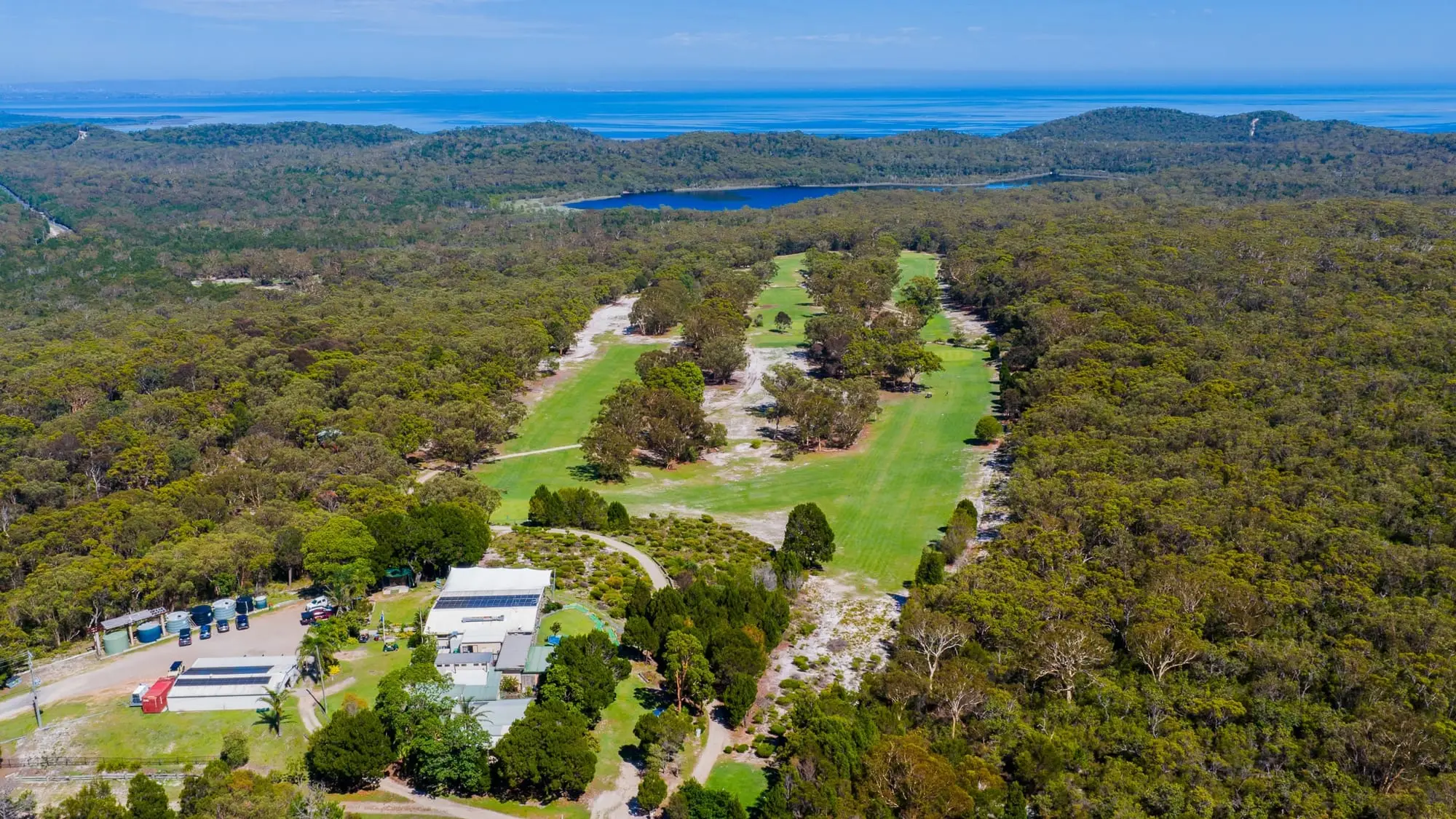 Aerial view of fairways and clubhouse surrounded by bush