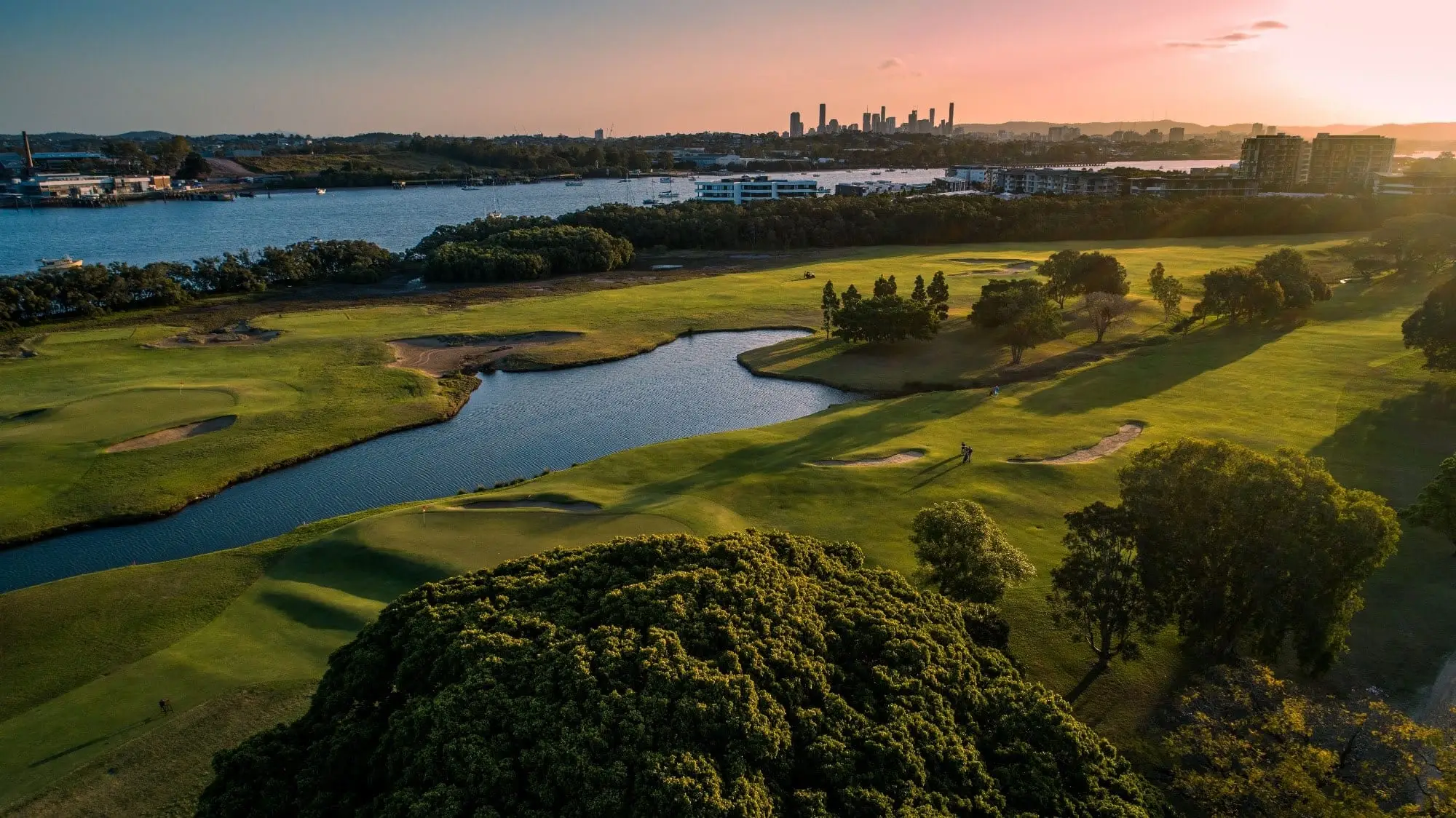 Aerial view of fairway, lake and river with city skyline