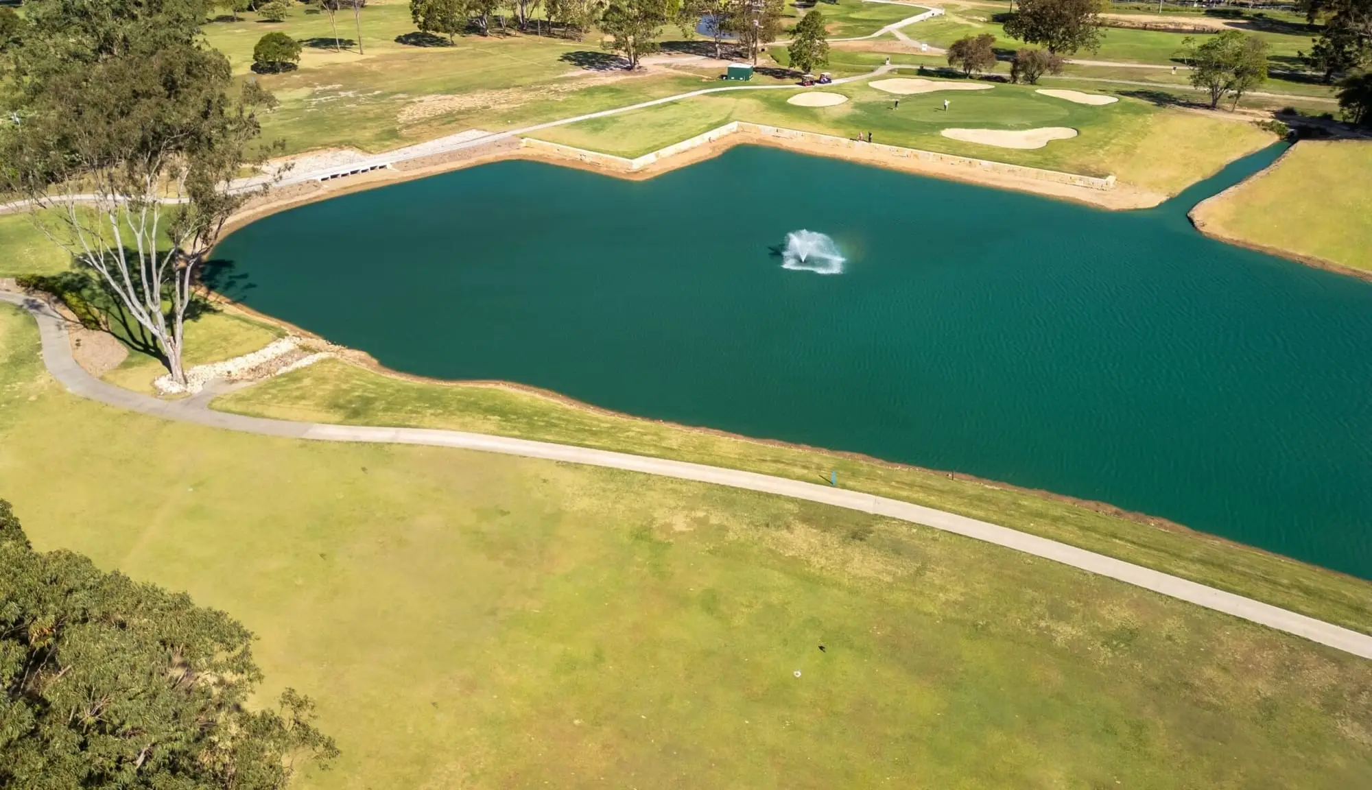 Aerial view of a lake with fountain beside a fairway
