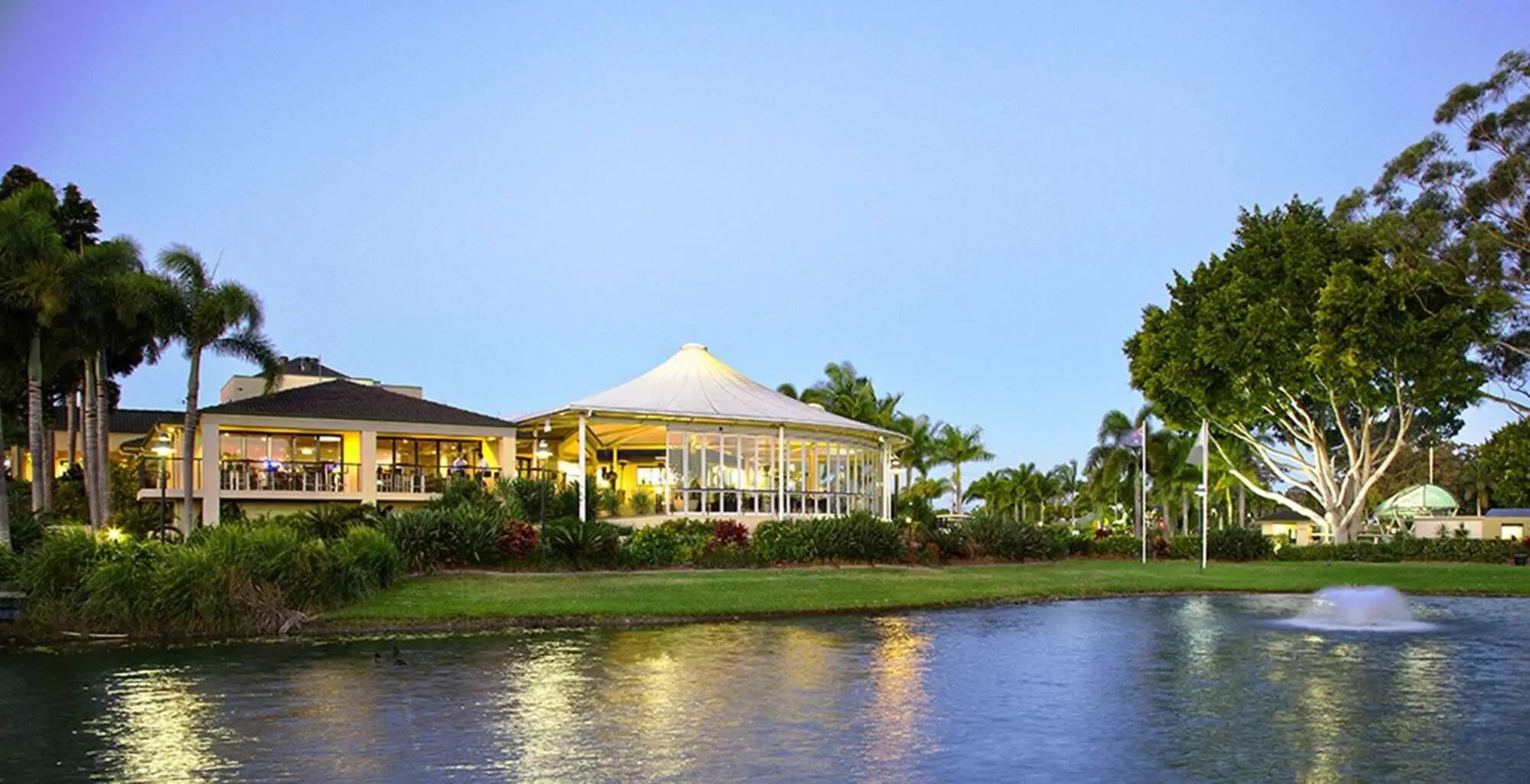 Clubhouse reflected in a lake with palms at dusk