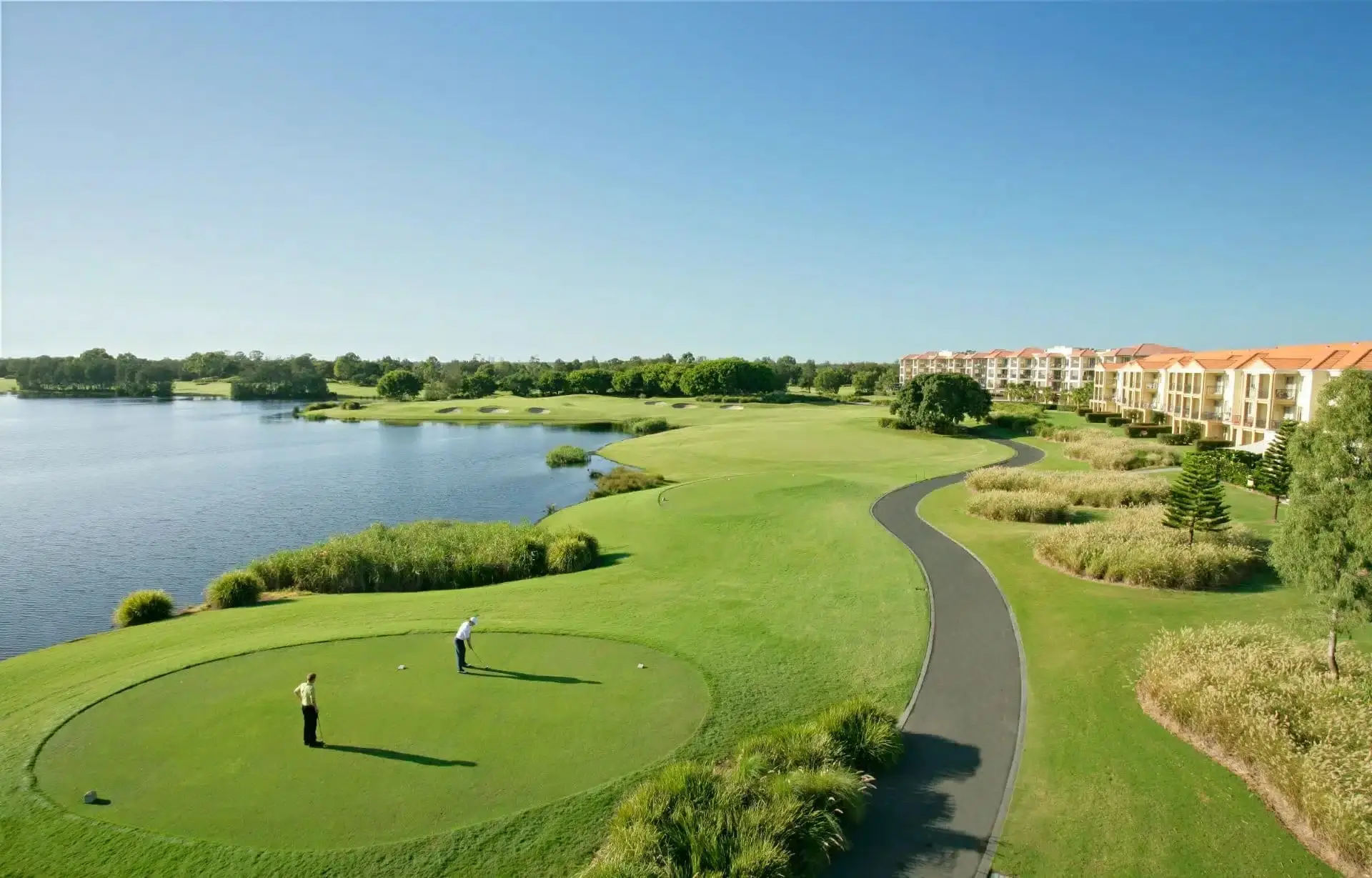 Tee and fairway beside a lake with apartments beyond