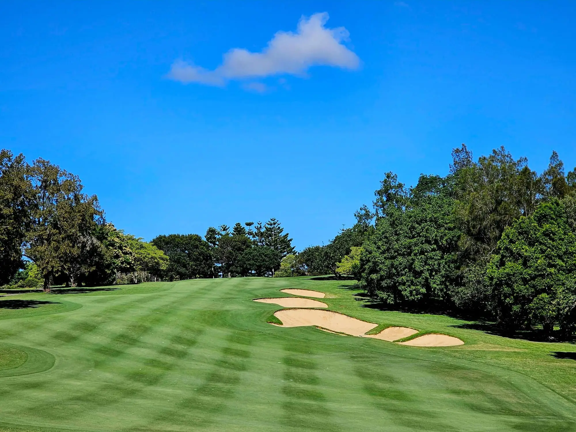 Striped fairway with bunkers under clear blue sky