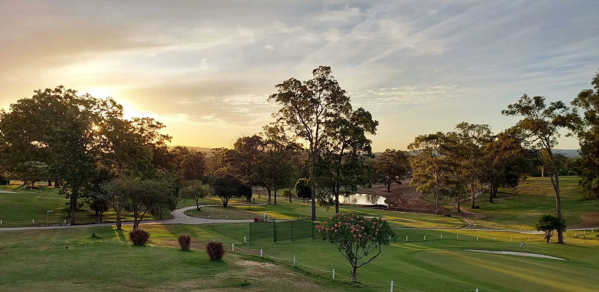 Sunset over clubhouse grounds, trees and fairway