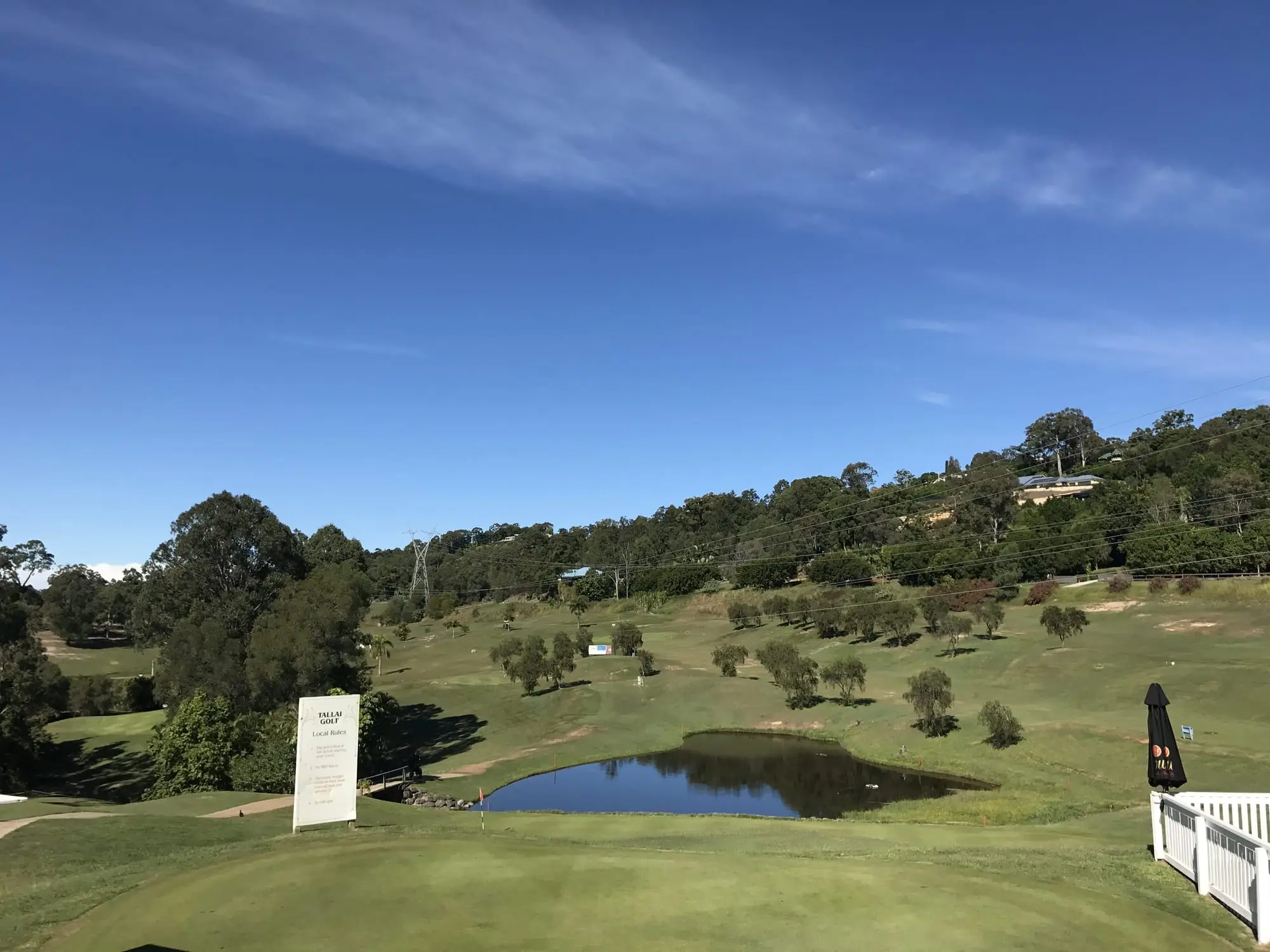 Pond and fairways on a hillside course under blue sky