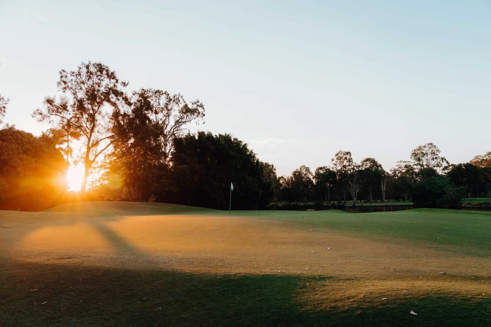 Sun setting over fairway and trees