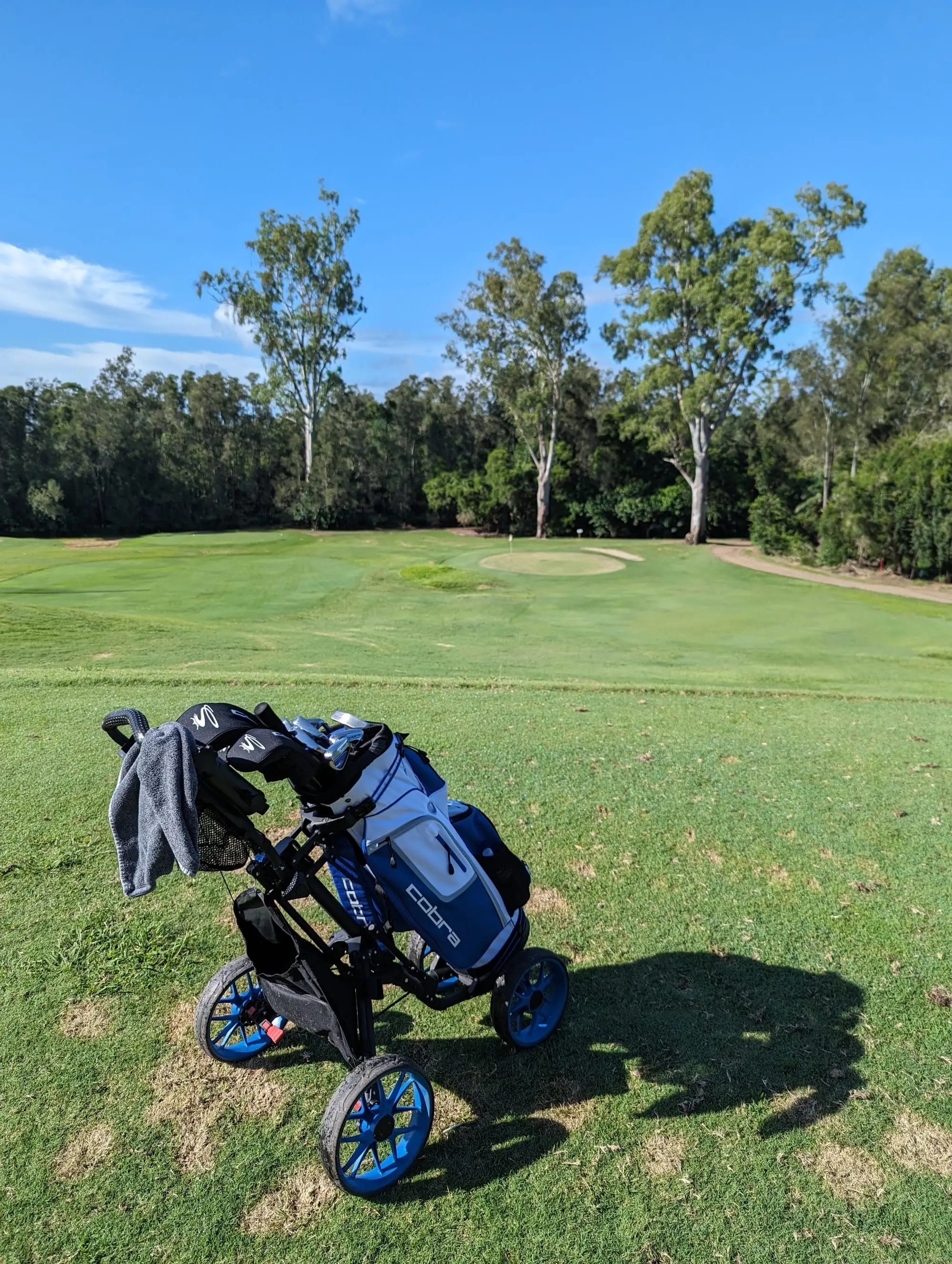 Fairway leading to a distant green with golf bag in foreground