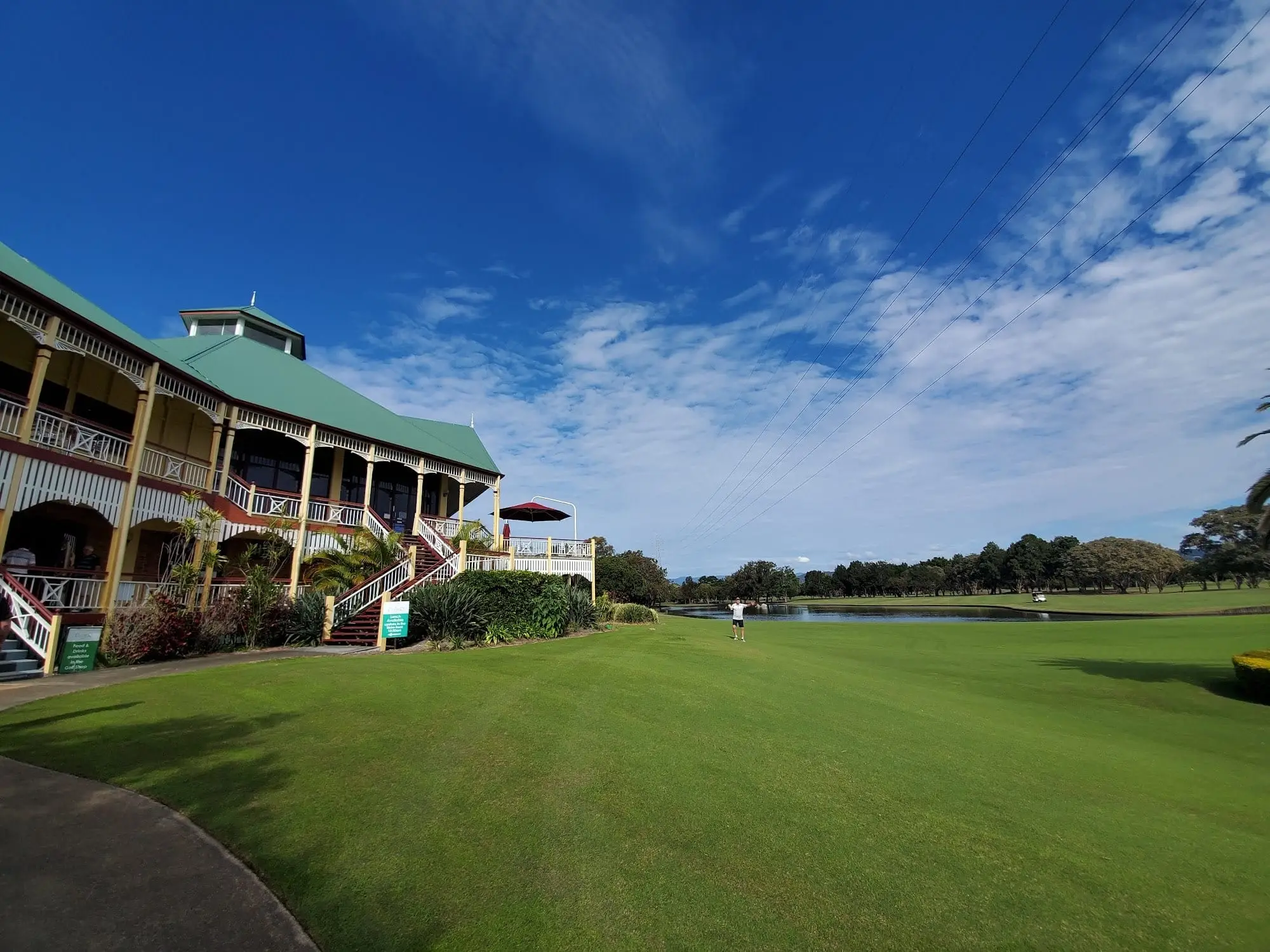 Queenslander-style clubhouse beside a fairway under blue sky