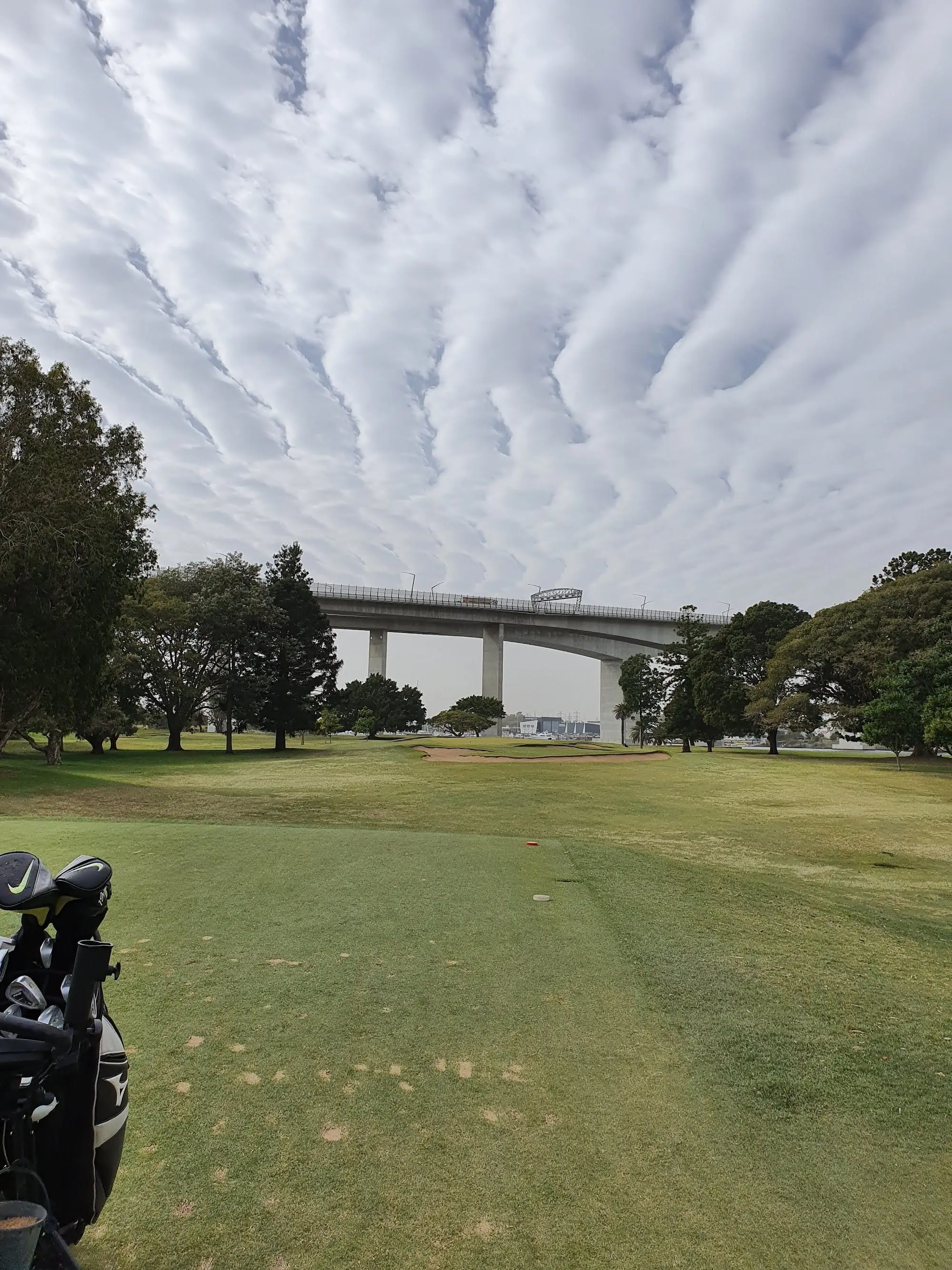 Fairway leading toward a bridge under a cloudy sky