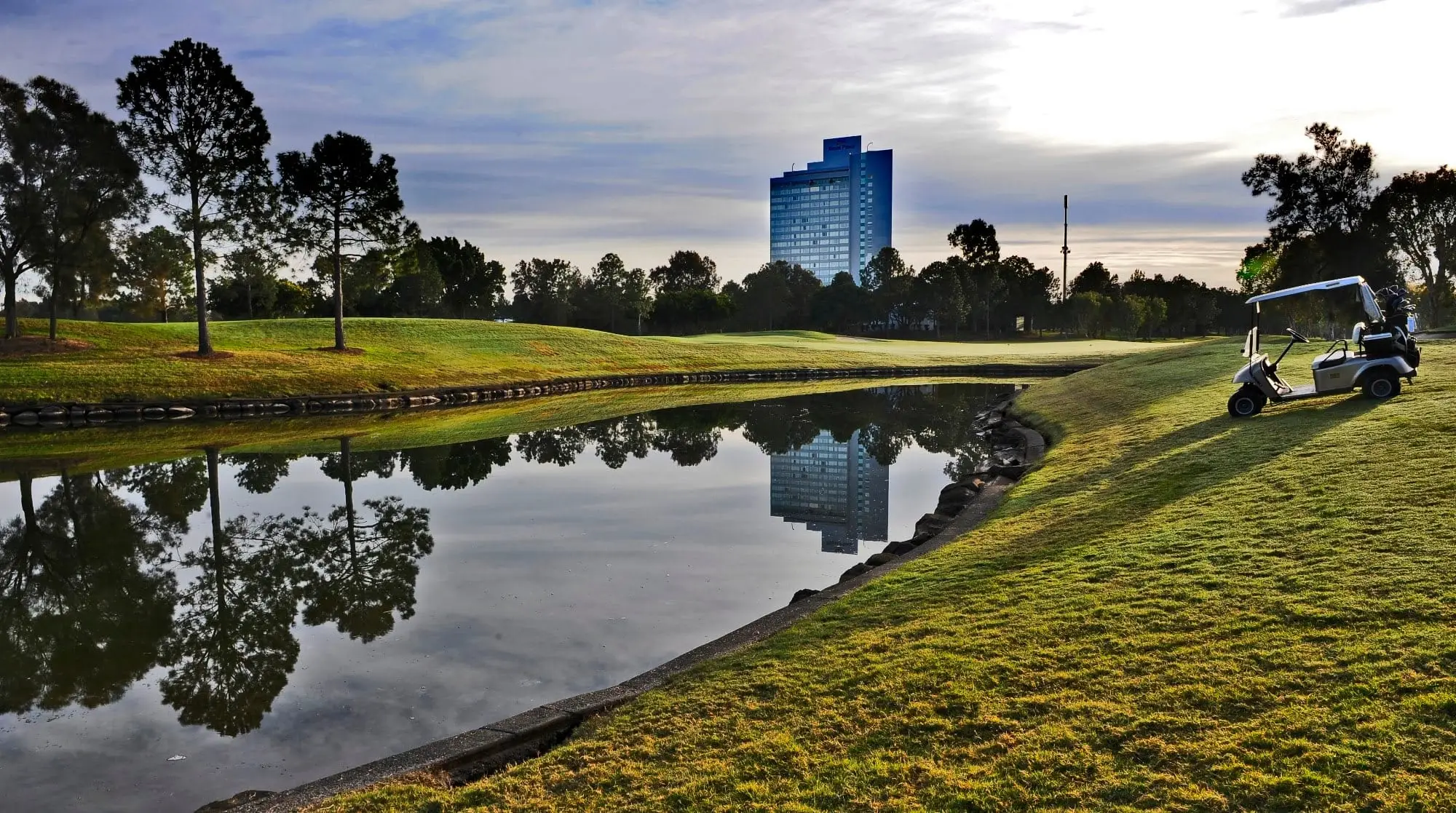 Lake reflecting resort tower beside a fairway