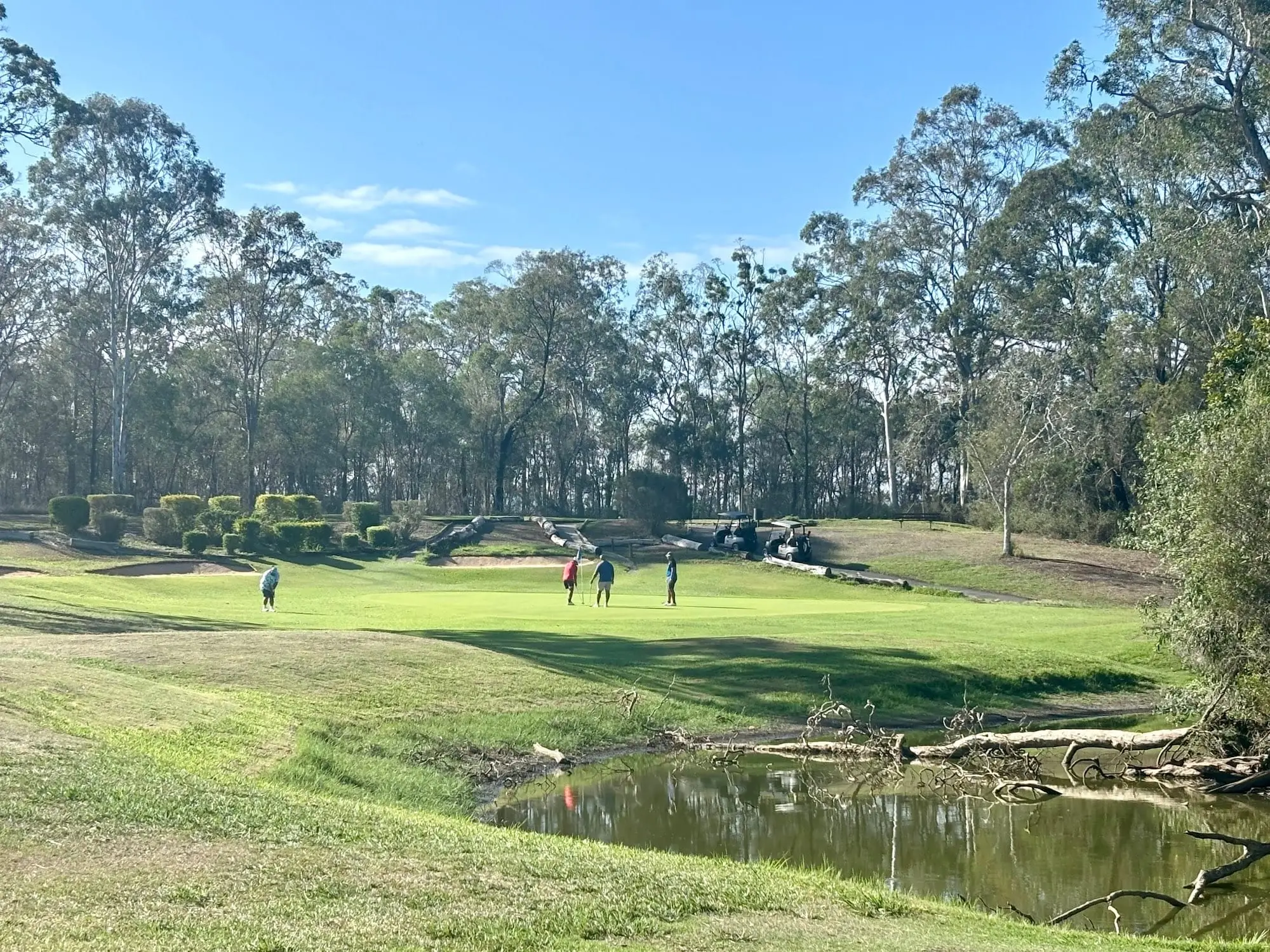 Fairway across a creek toward a green with golfers