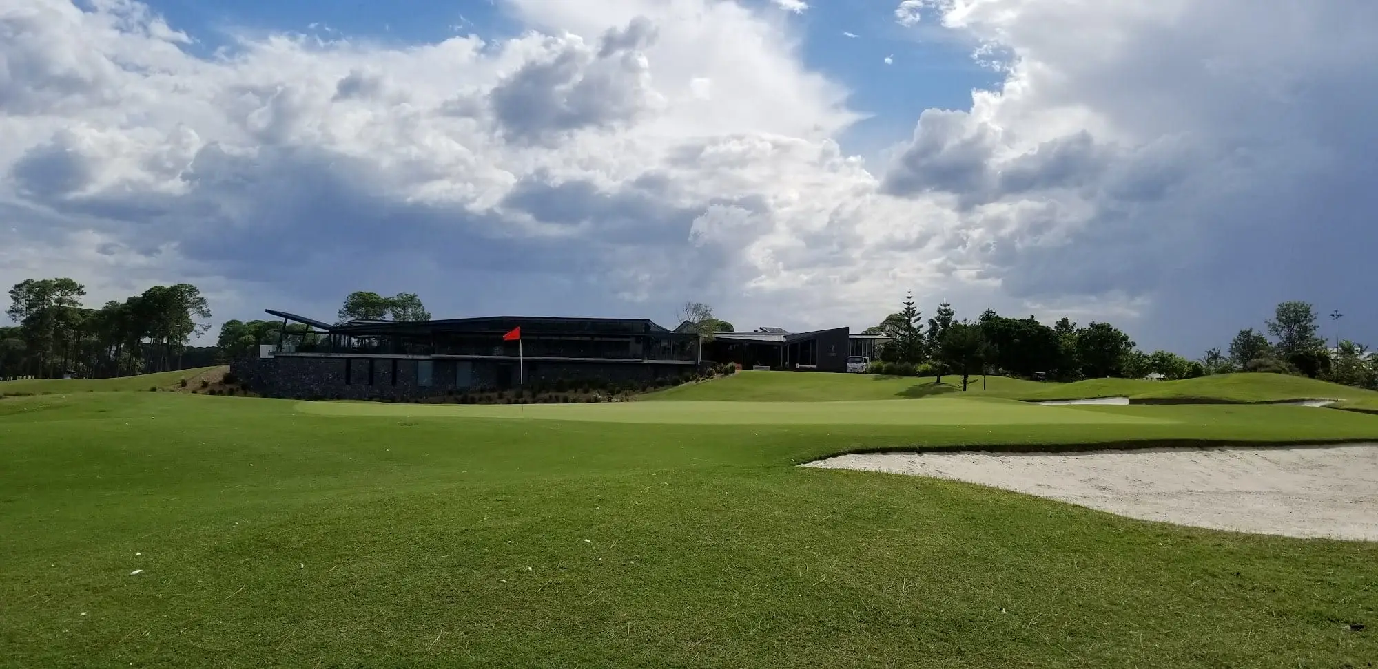 Modern clubhouse behind a bunker and green