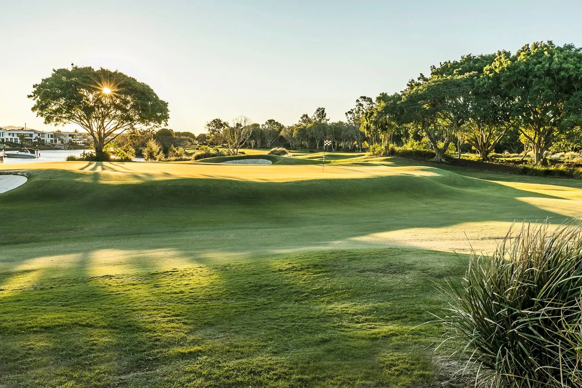Late sun over a fairway with trees and distant lake