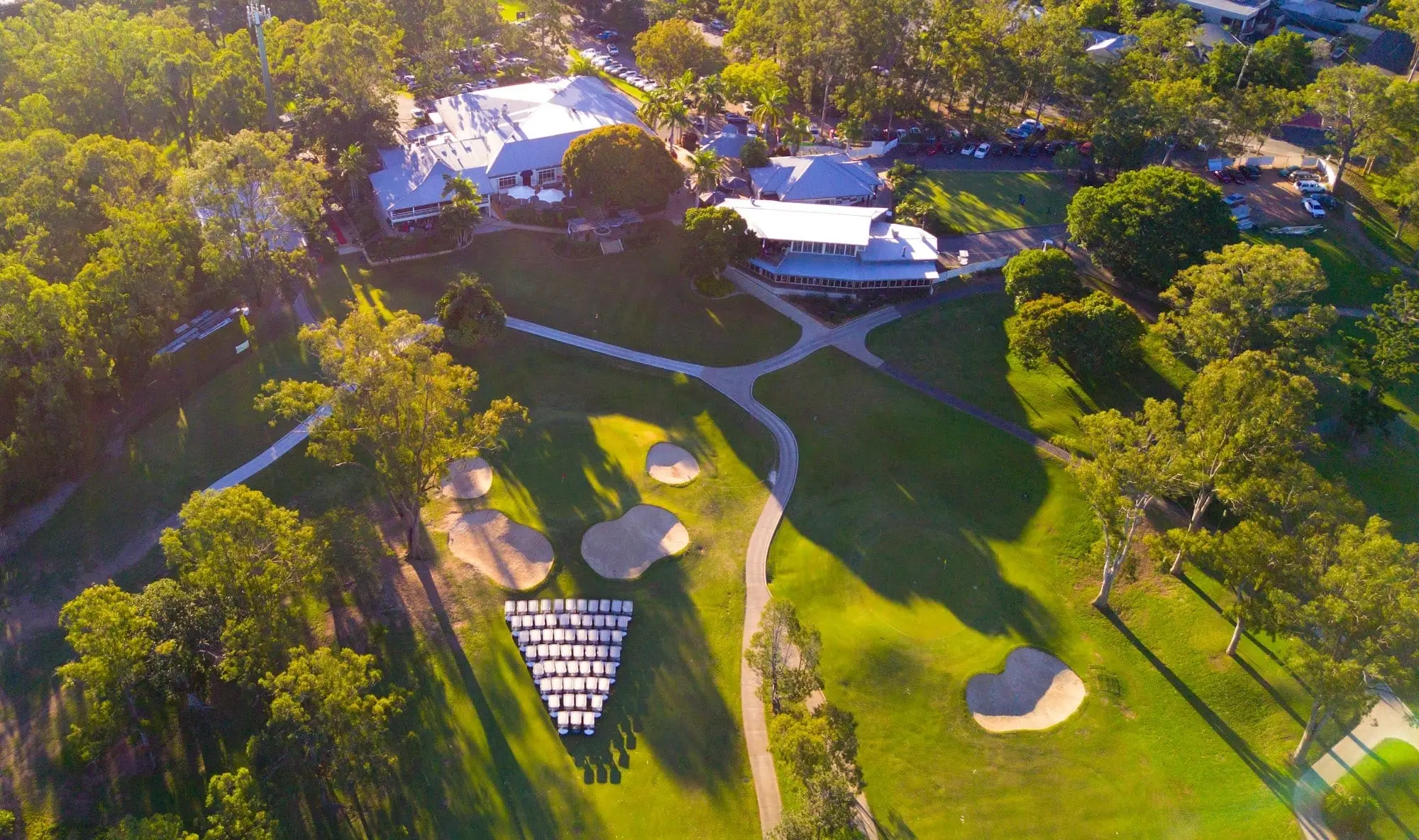 Aerial of clubhouse among trees beside the course