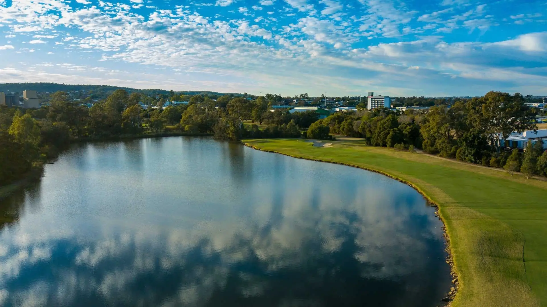 Lake beside a fairway reflecting blue sky and clouds