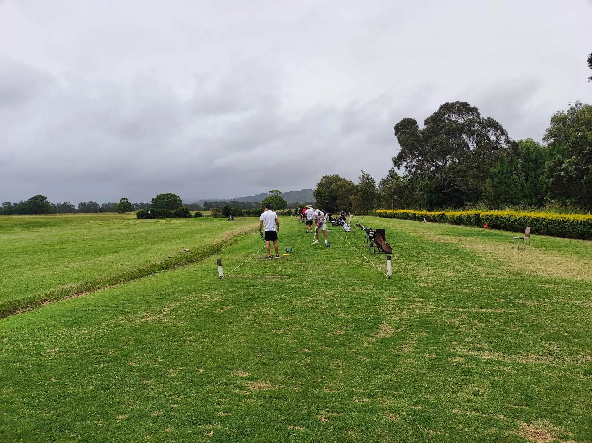Long straight fairway under cloudy sky with golfers in the distance