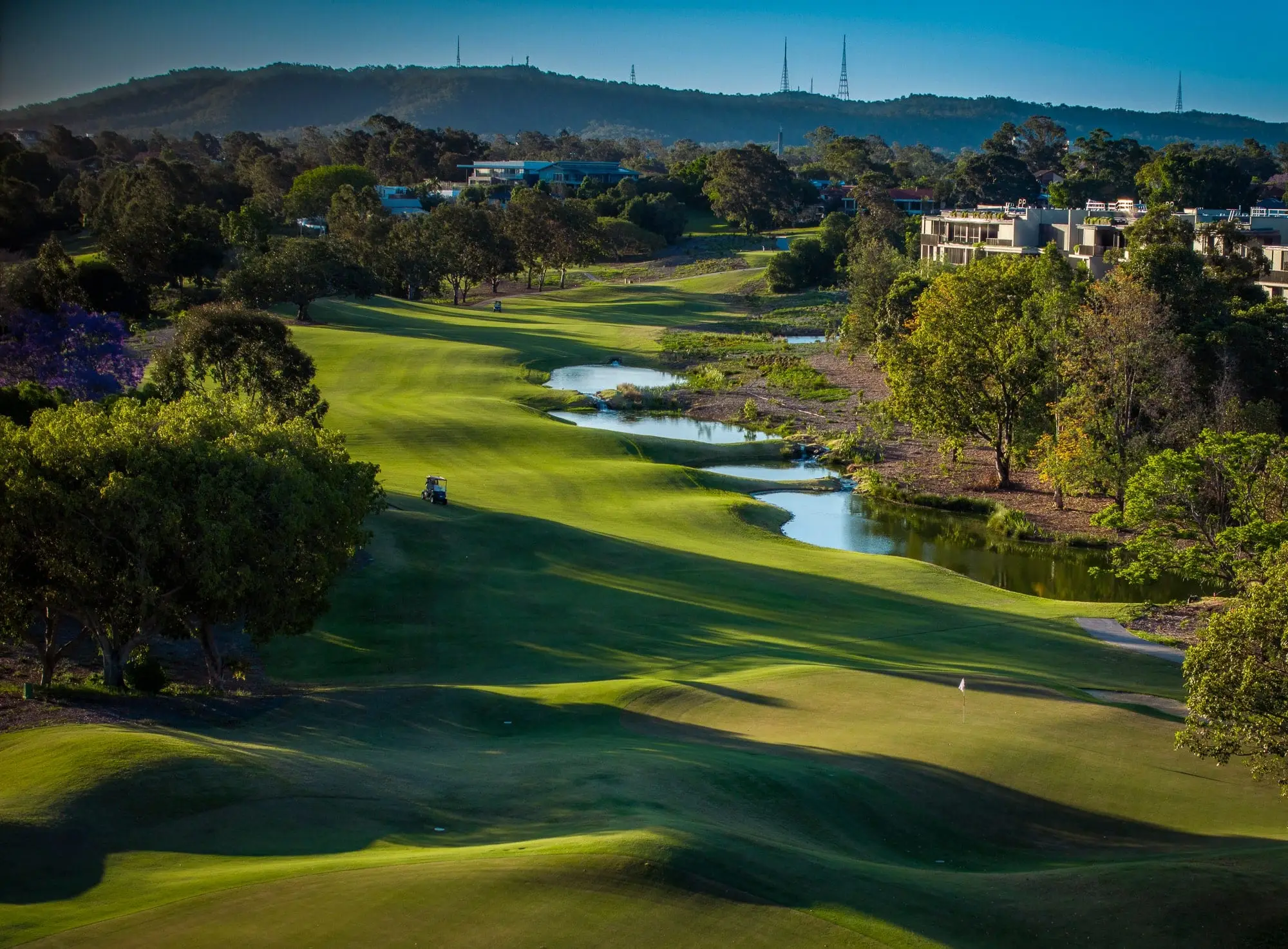 Fairway curving beside creek with hills behind