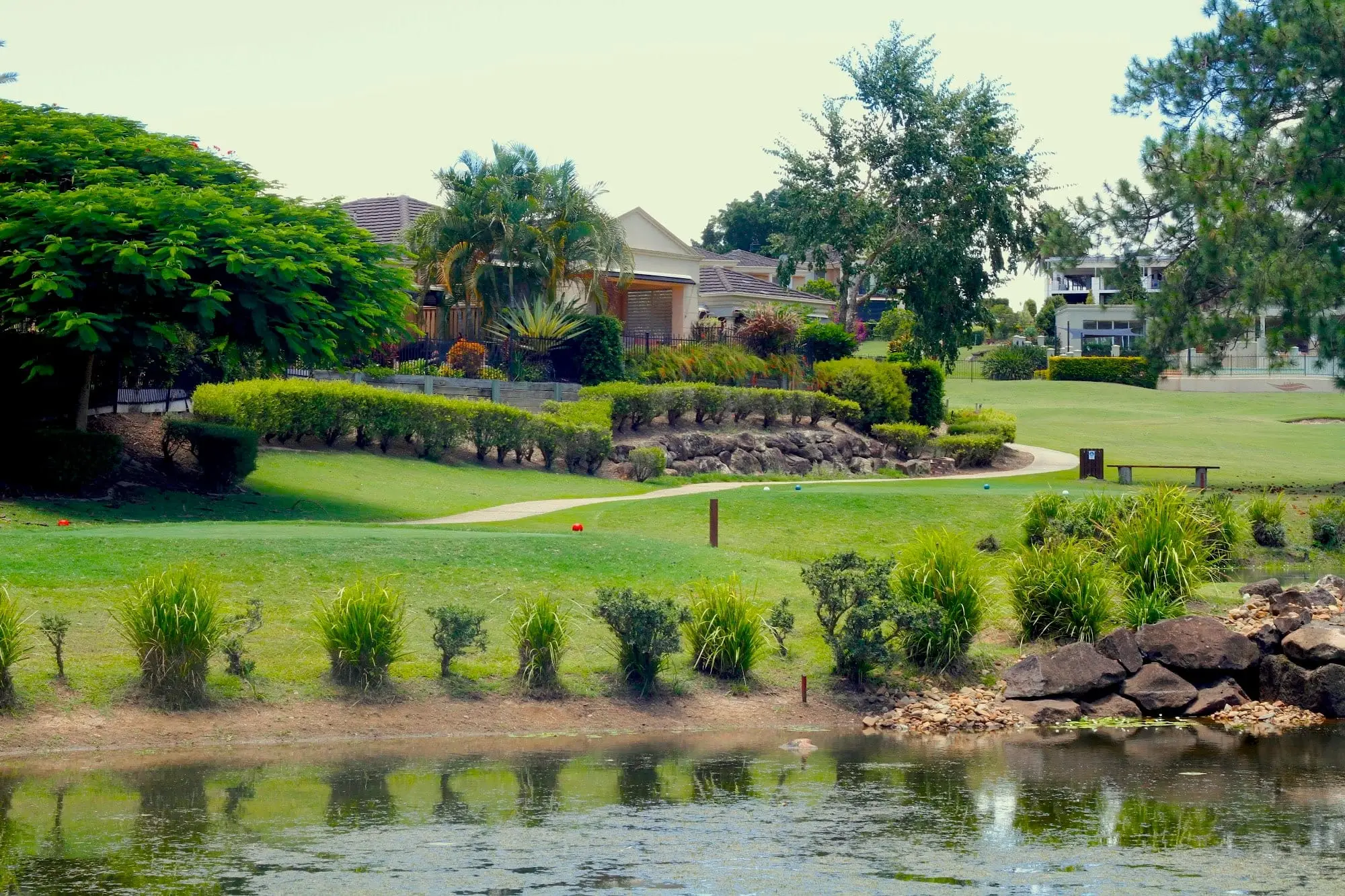 Landscaped pond and rock garden beside a fairway and homes