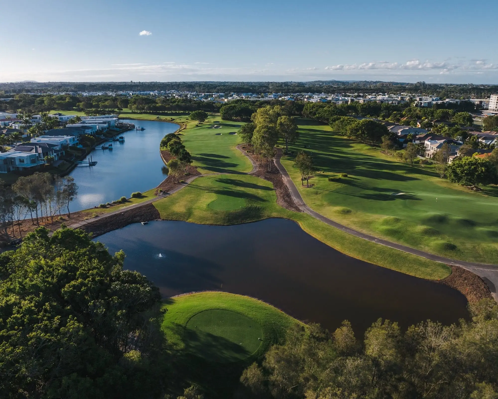 Aerial view of fairway running between lake and housing