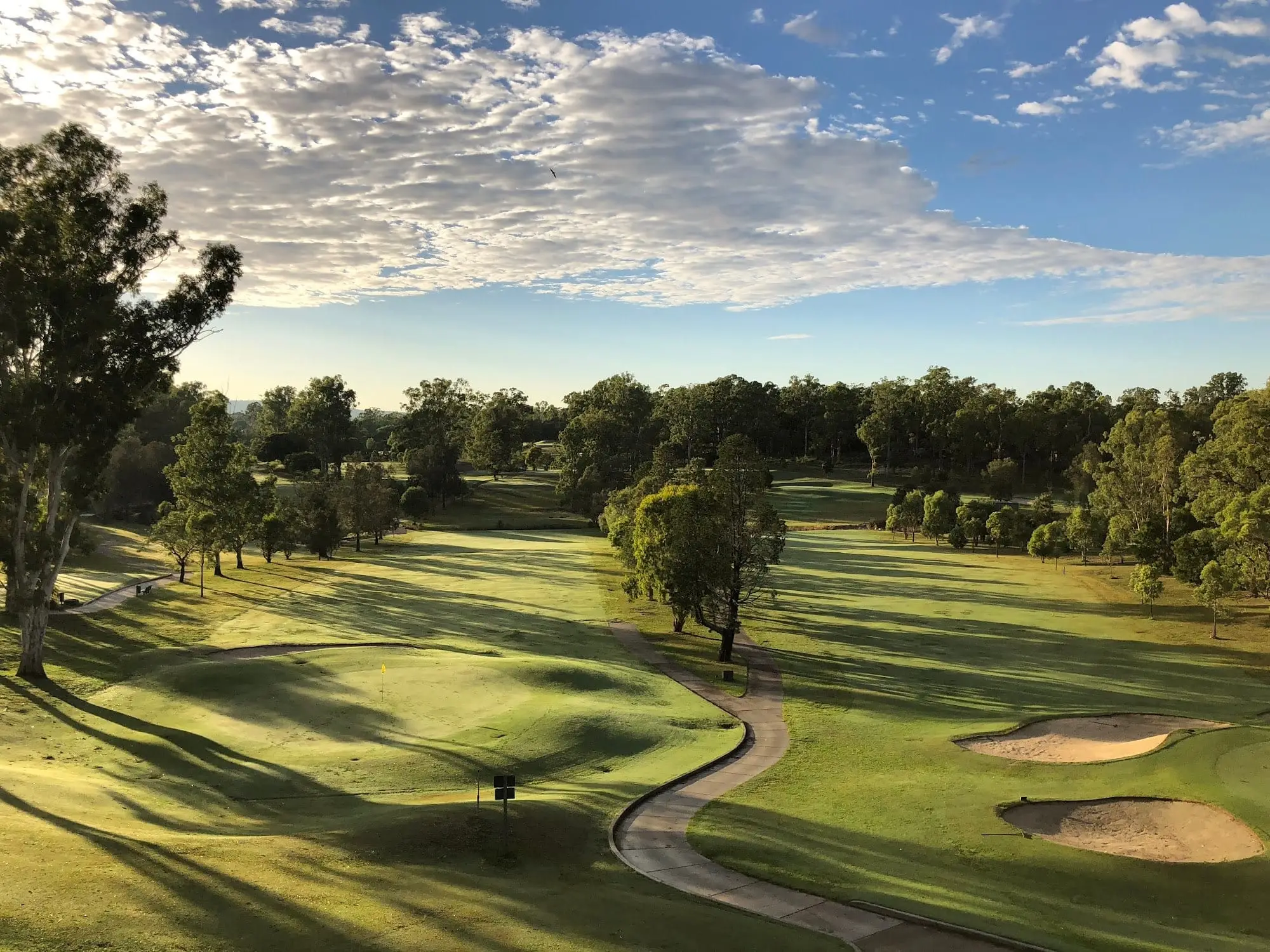 Fairway and bunkers with tree-lined course at sunset