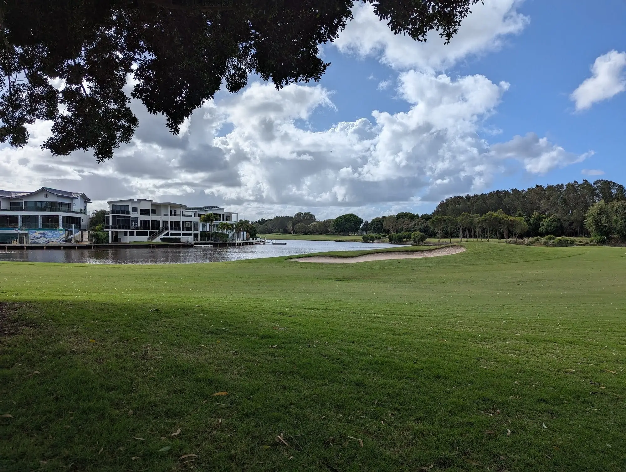 Fairway beside a lake with waterfront houses and cloud