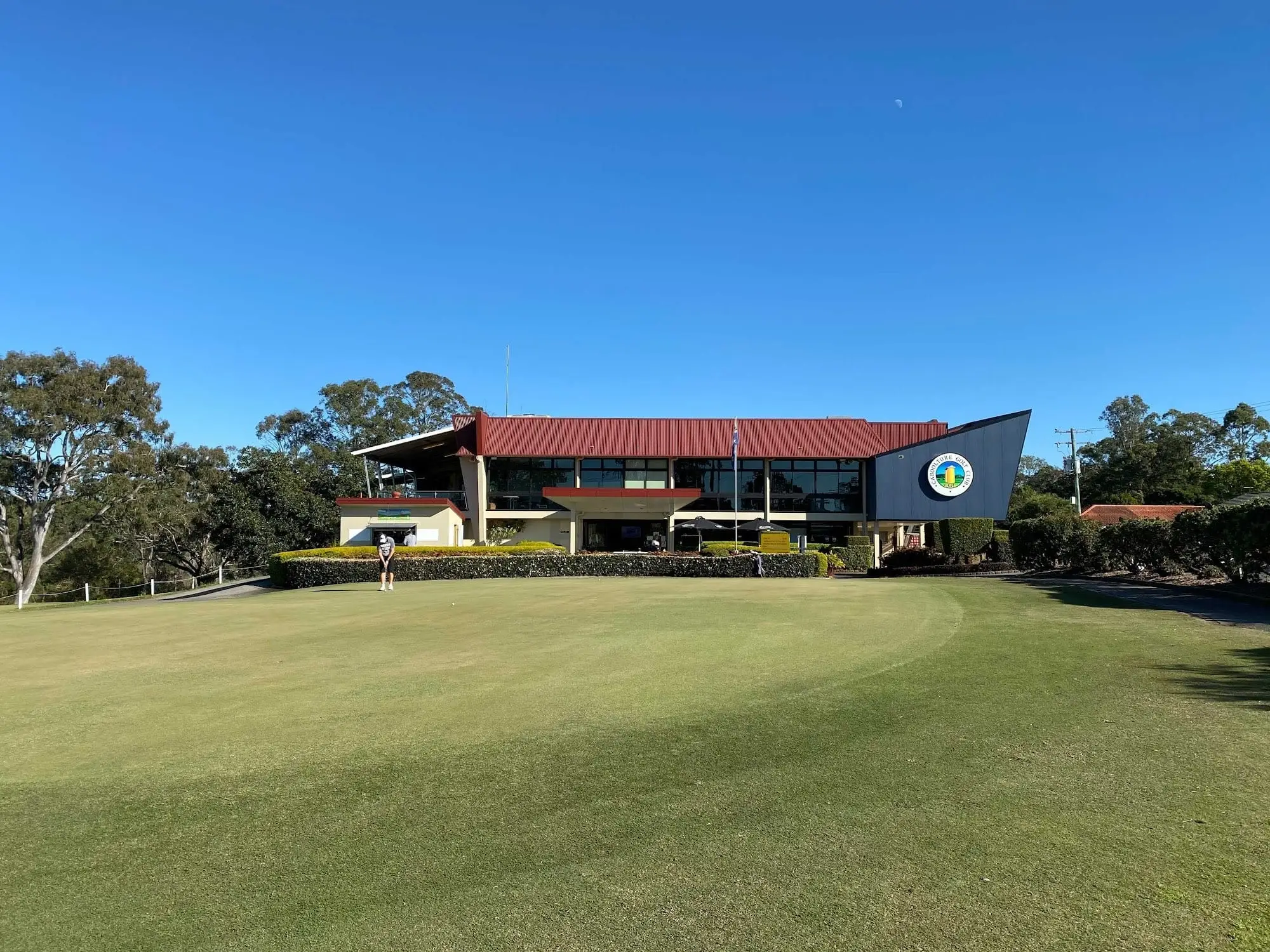 Brick clubhouse with course in front under clear blue sky