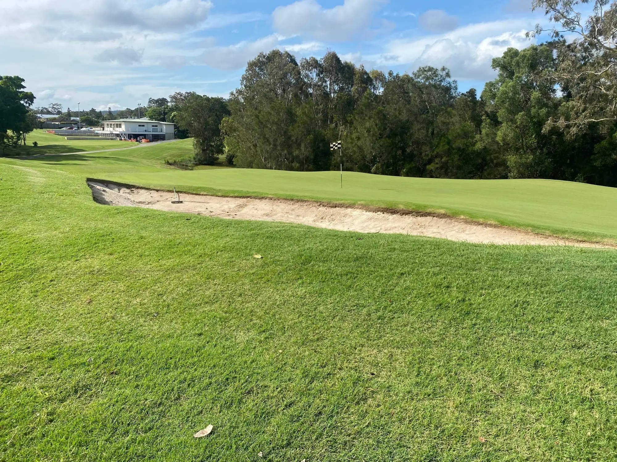 Fairway bunker with clubhouse and trees in distance