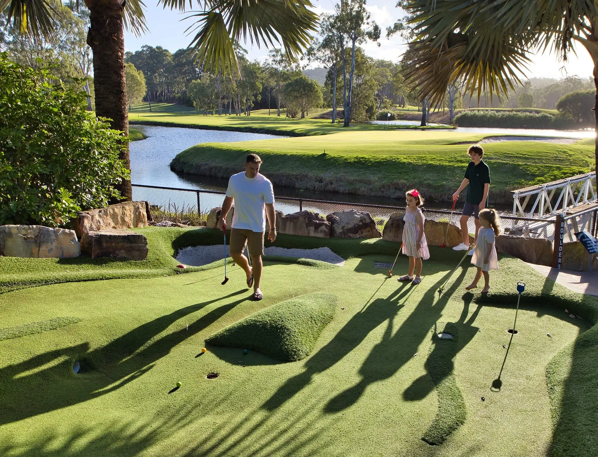 Family playing mini golf beside a lake and the course