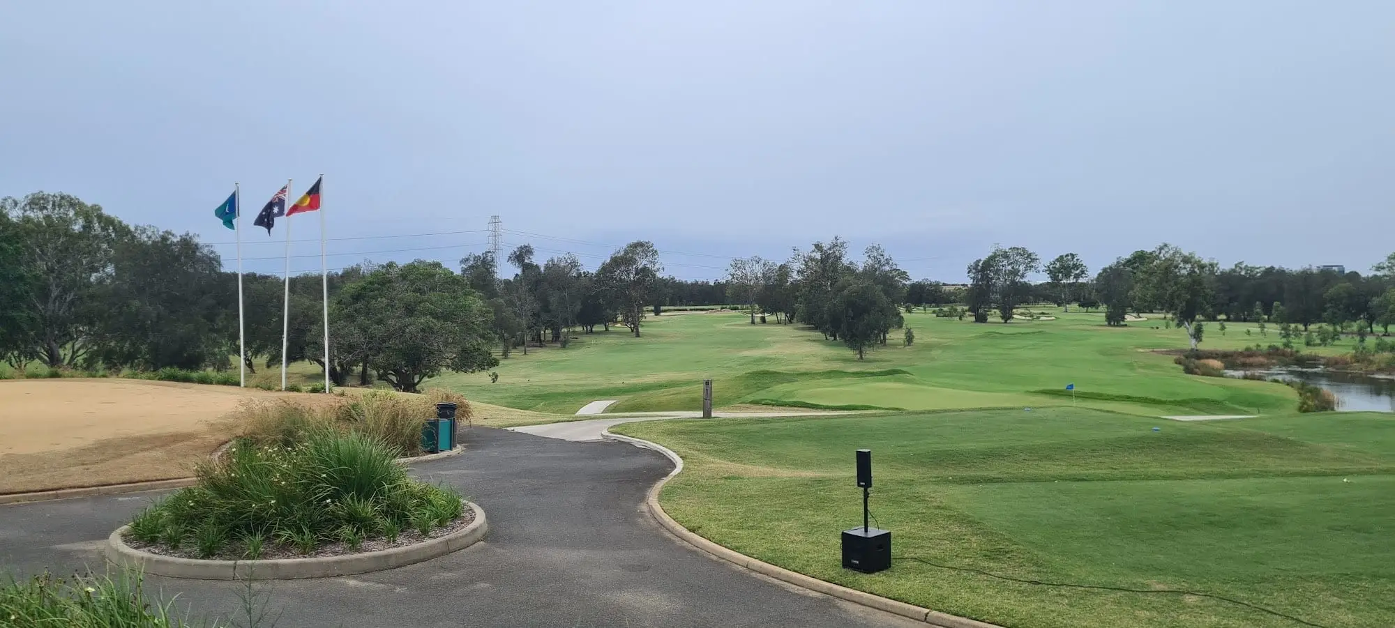 Cart path curving to a tee with flags and open fairway