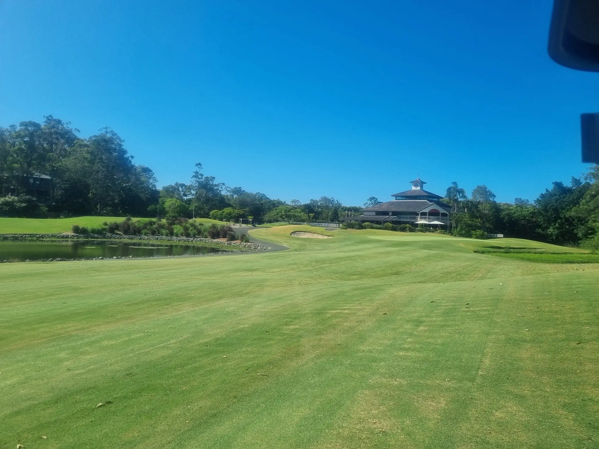 Wide fairway with clubhouse in the distance under blue sky