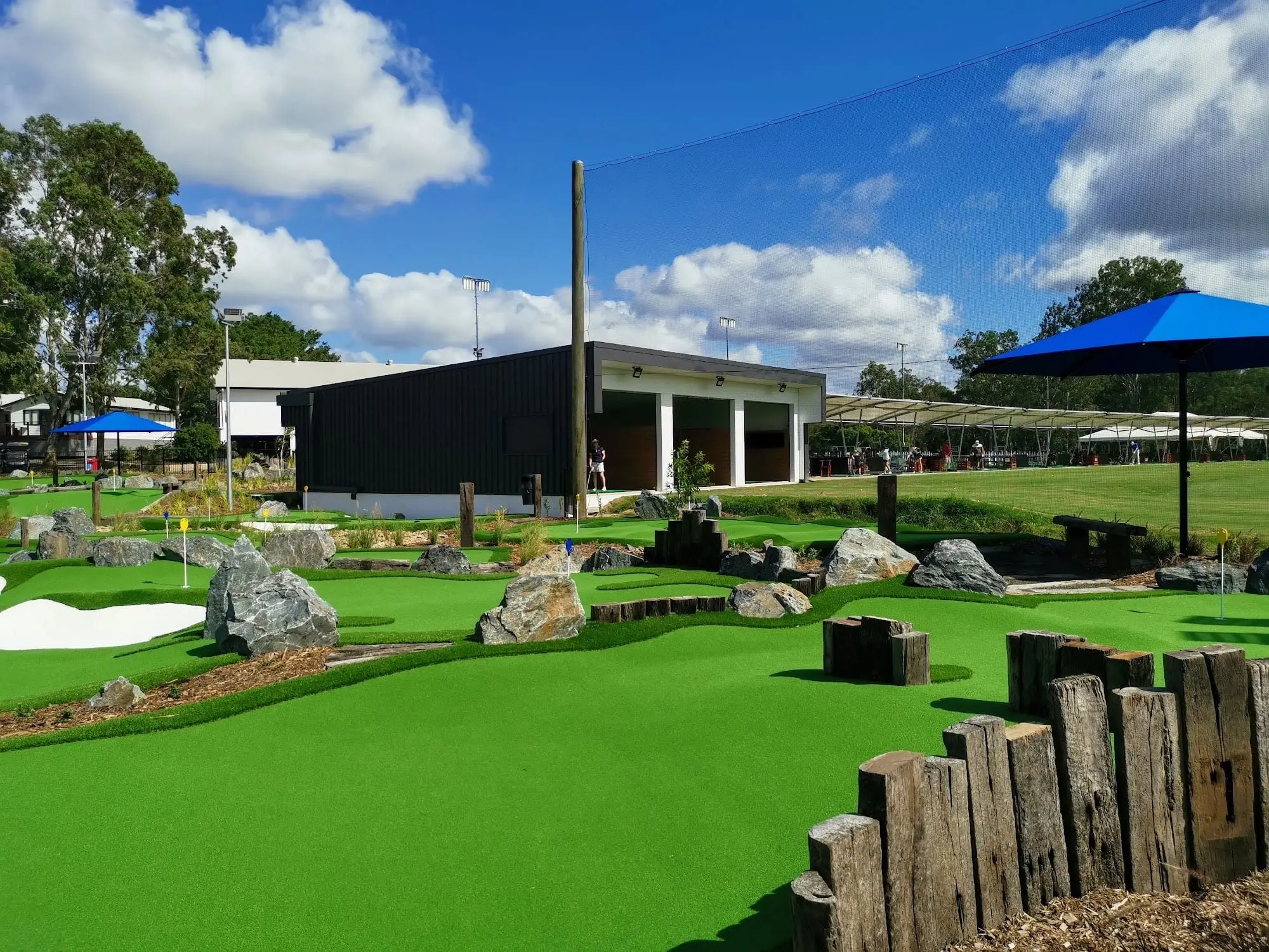 Landscaped mini golf course with rocks and clubhouse behind