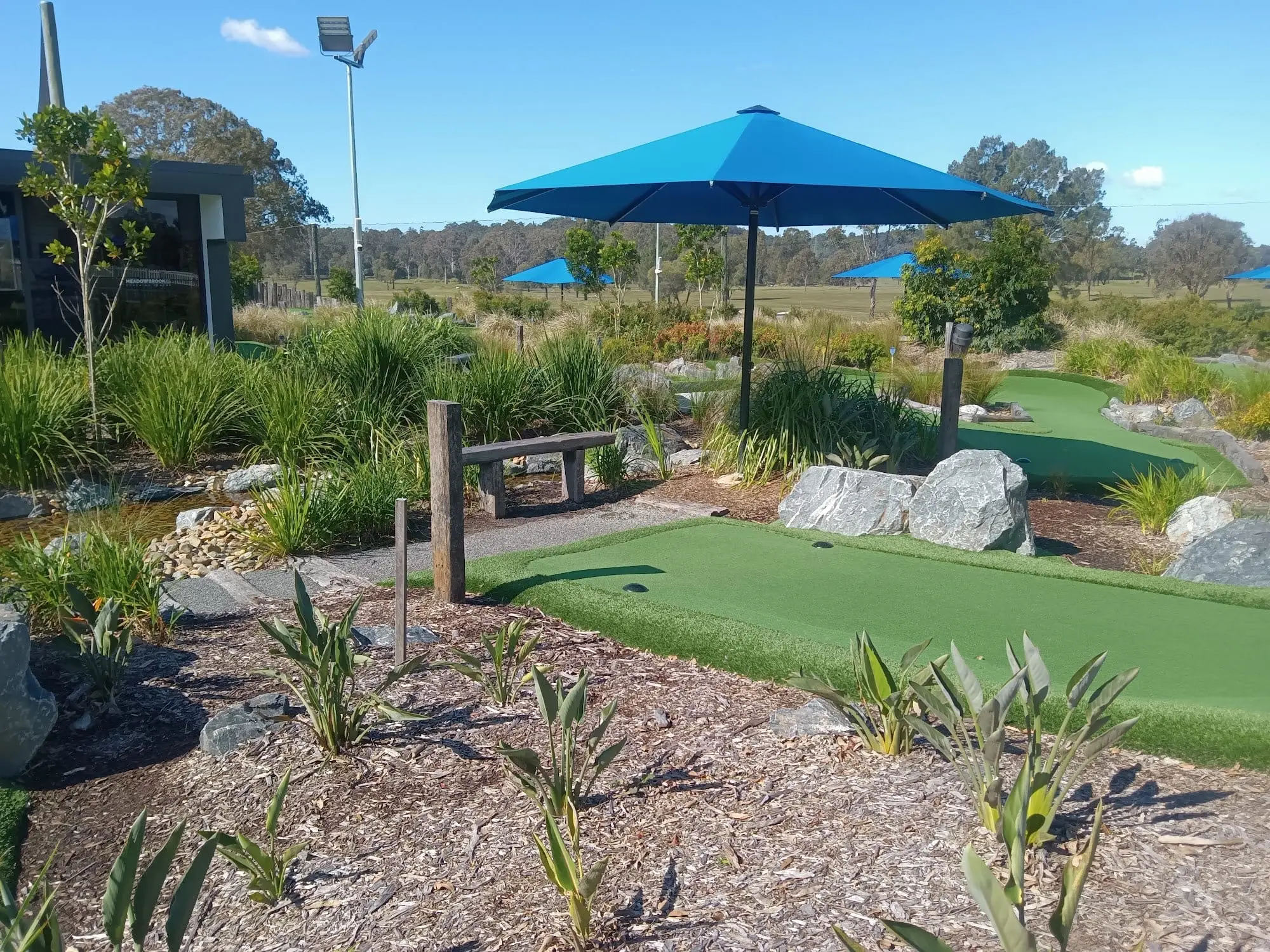 Putting course with boulders, native plants and umbrella shade