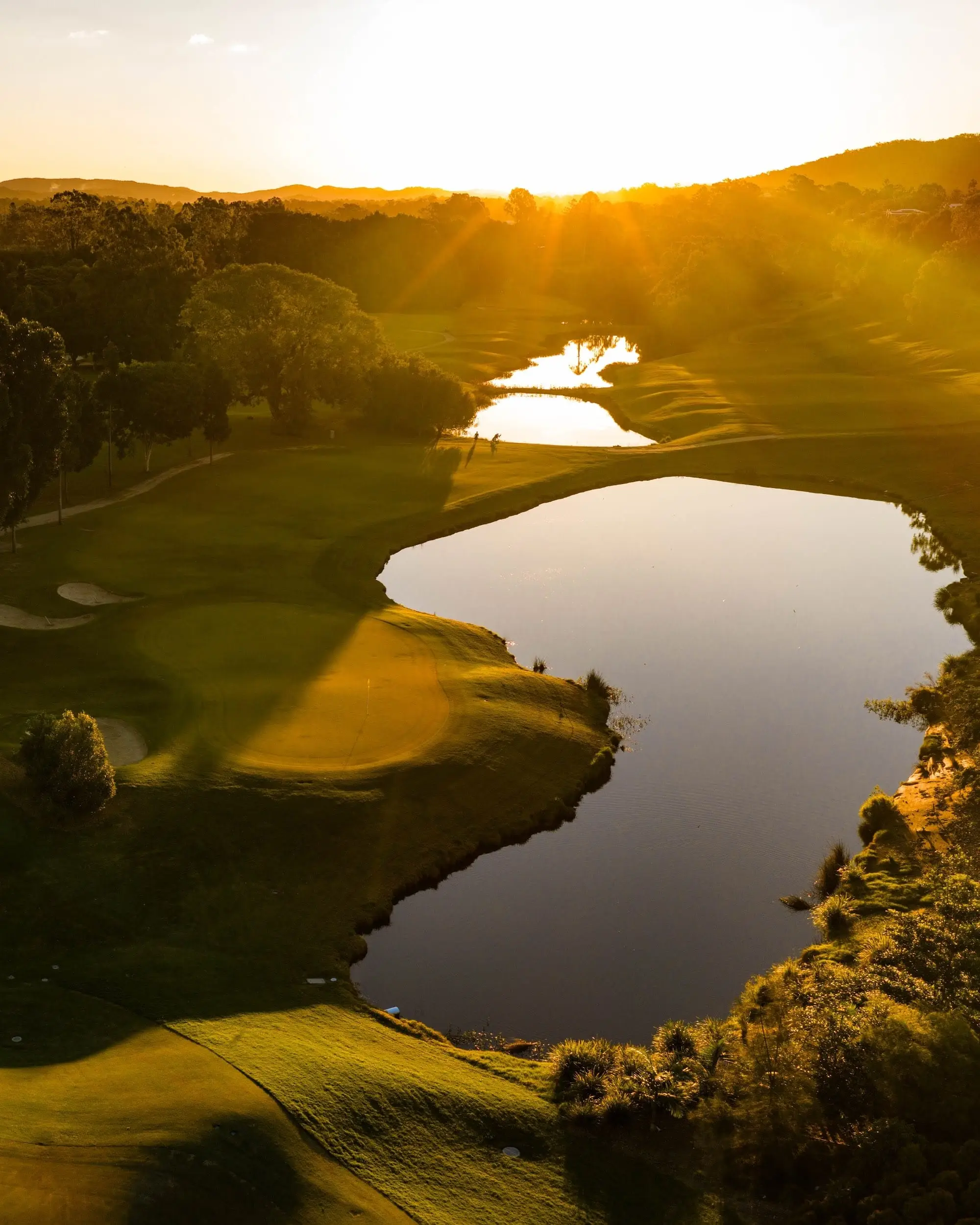 Lake beside a green at golden hour from above