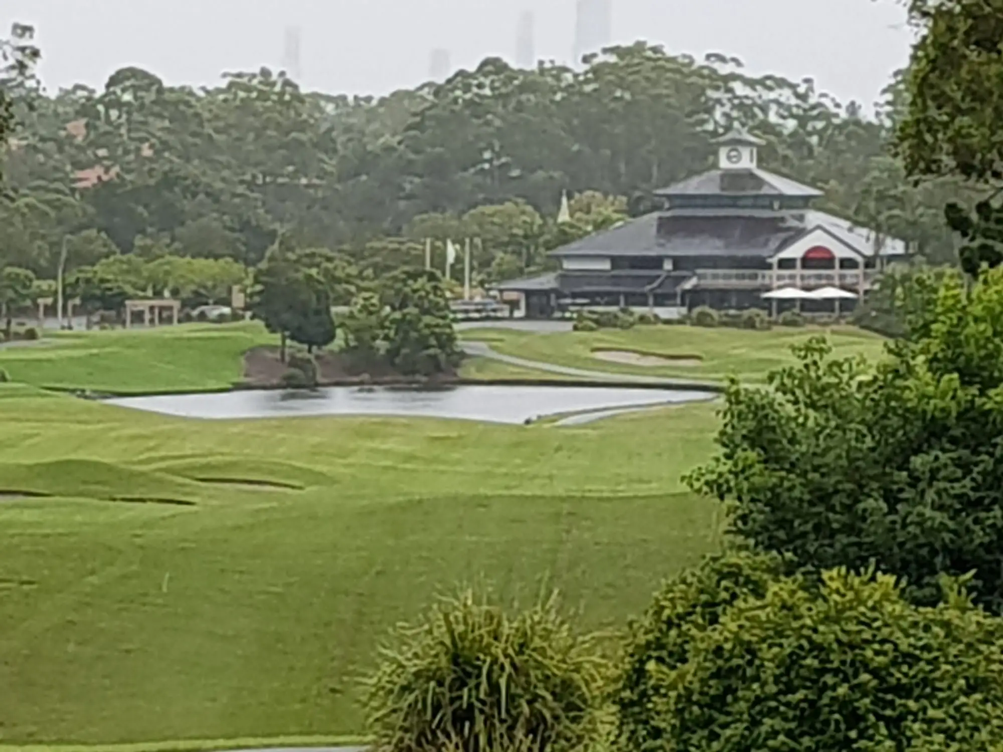 Clubhouse across a lake and bunkered fairway