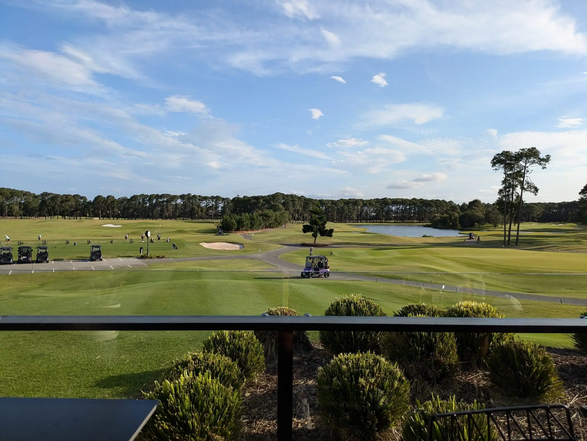 Fairway view from the clubhouse deck with buggies and a pond