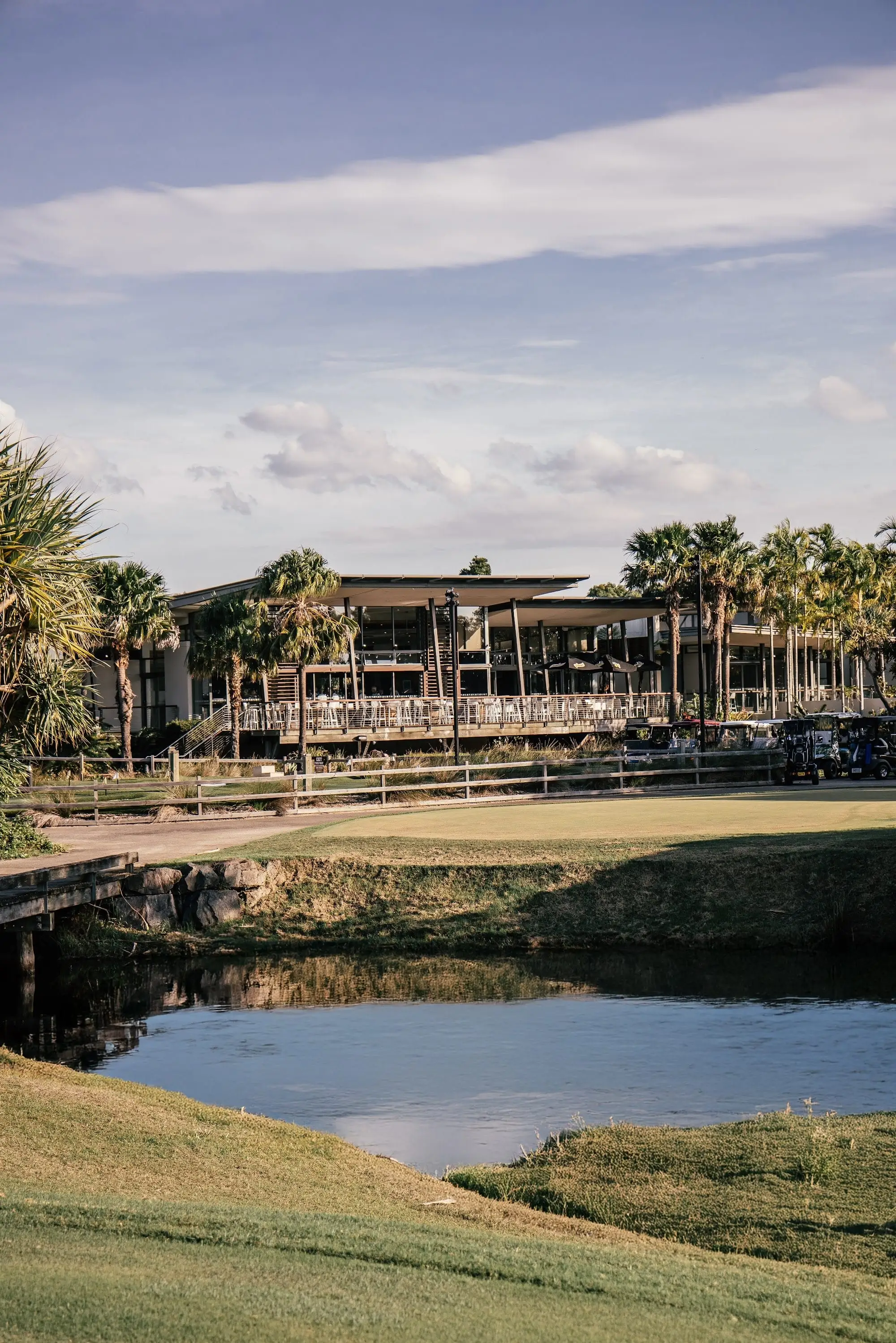 Clubhouse and palms behind a green and water hazard