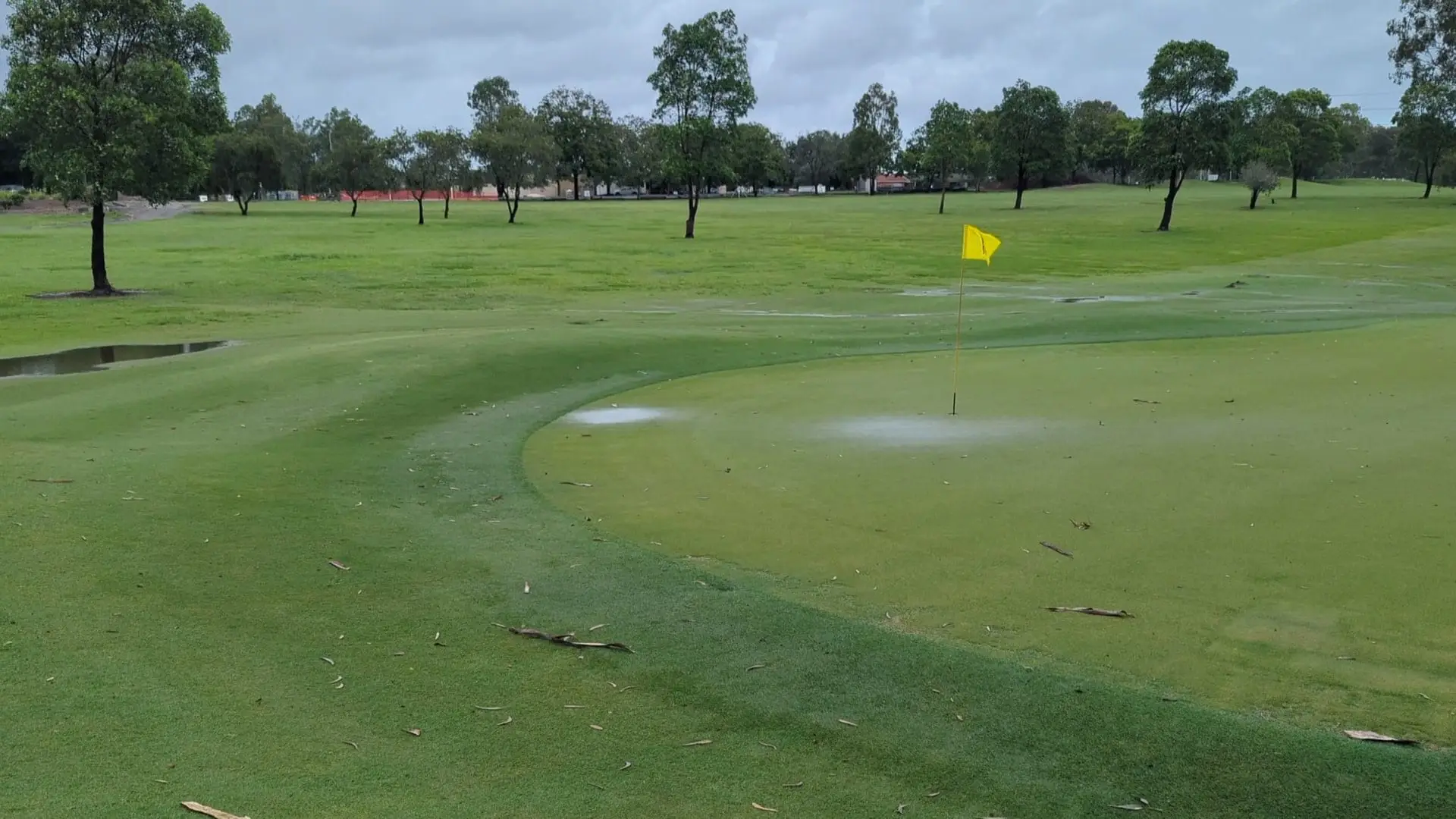 Green with yellow flag and wide fairway beyond