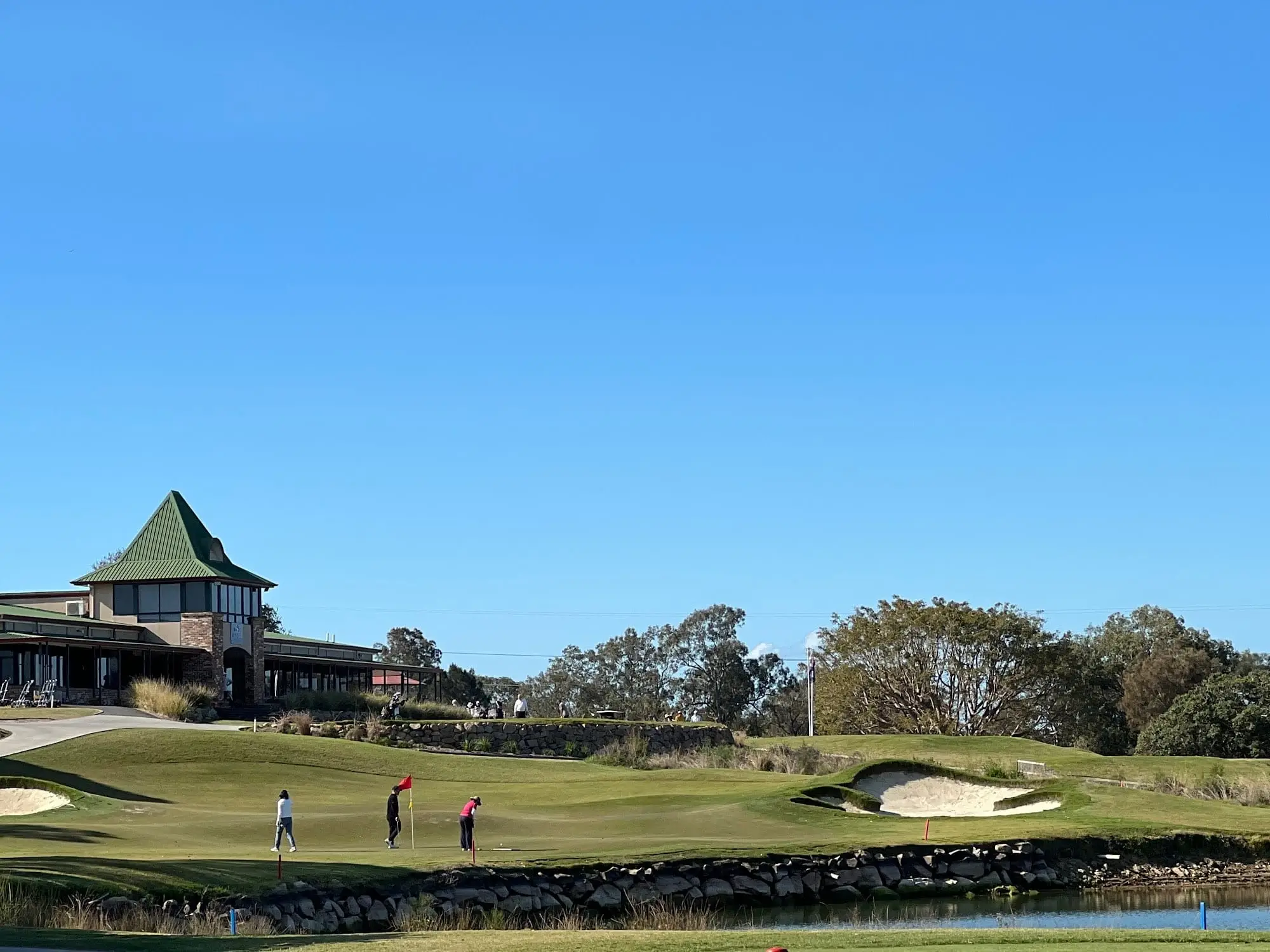 Clubhouse with pagoda roof behind a bunker and fairway