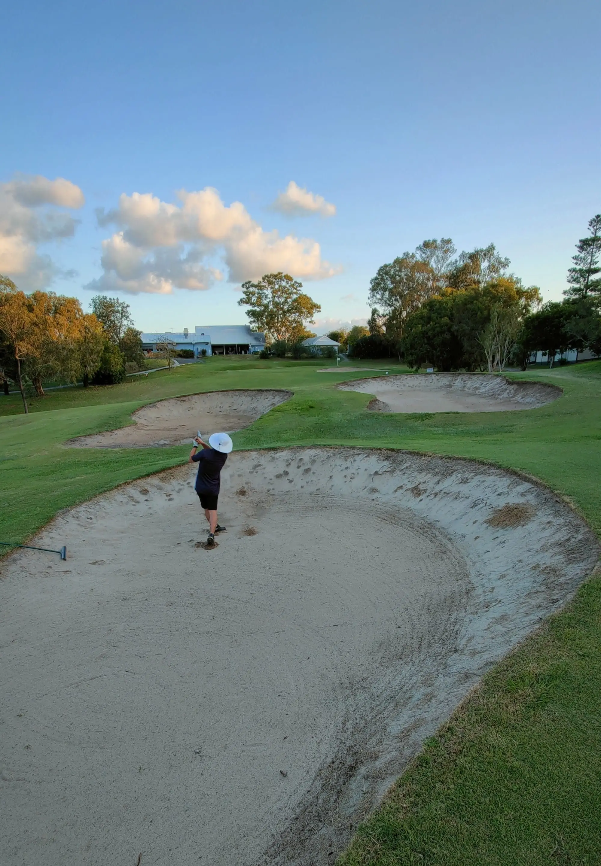 Greenside bunker with the clubhouse visible across the course