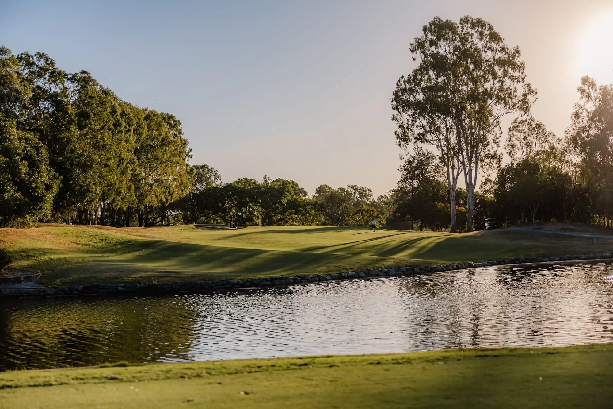 Water hazard beside a fairway with gum trees at sunset