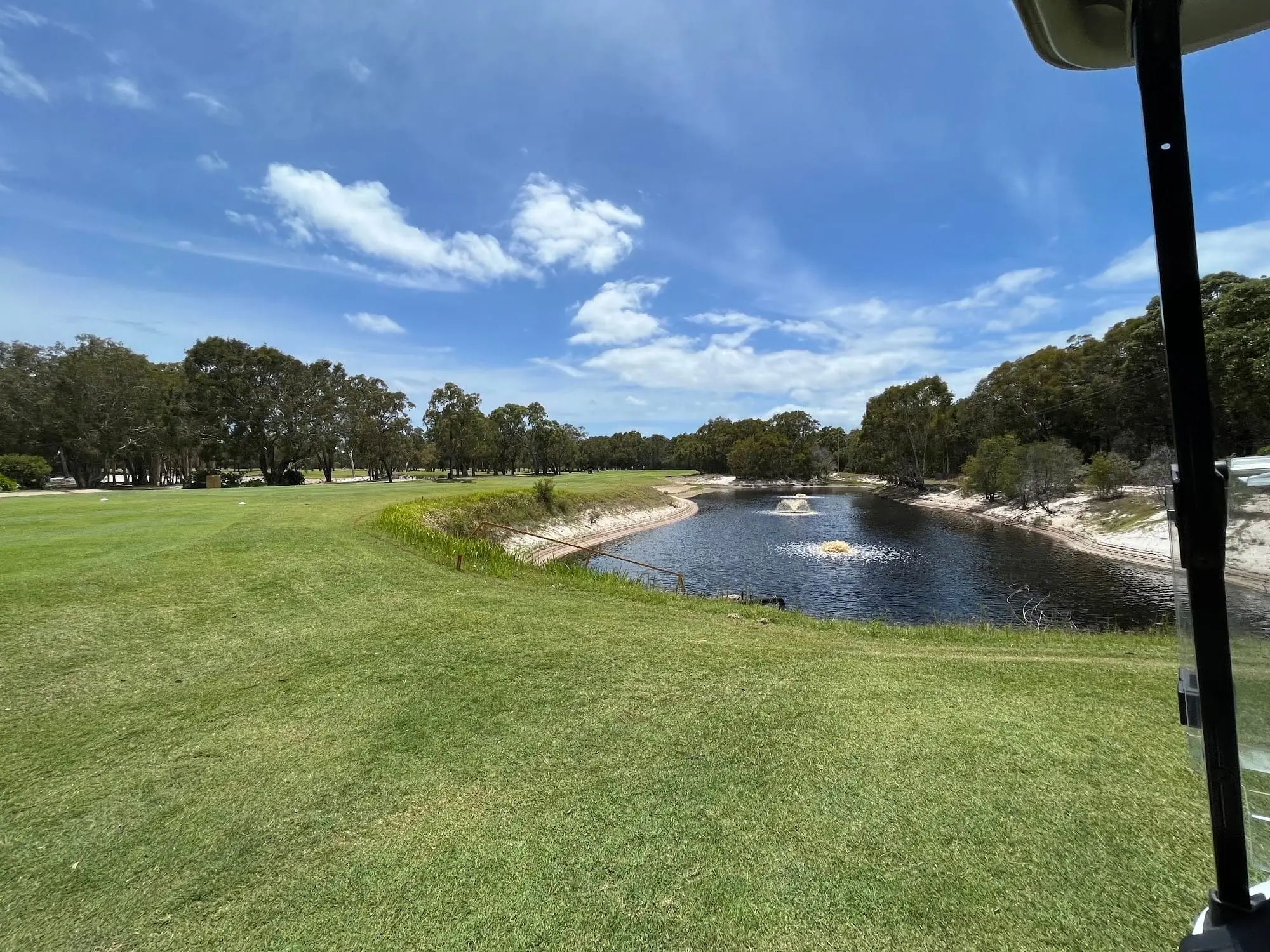 Wide pond beside a fairway under a blue sky