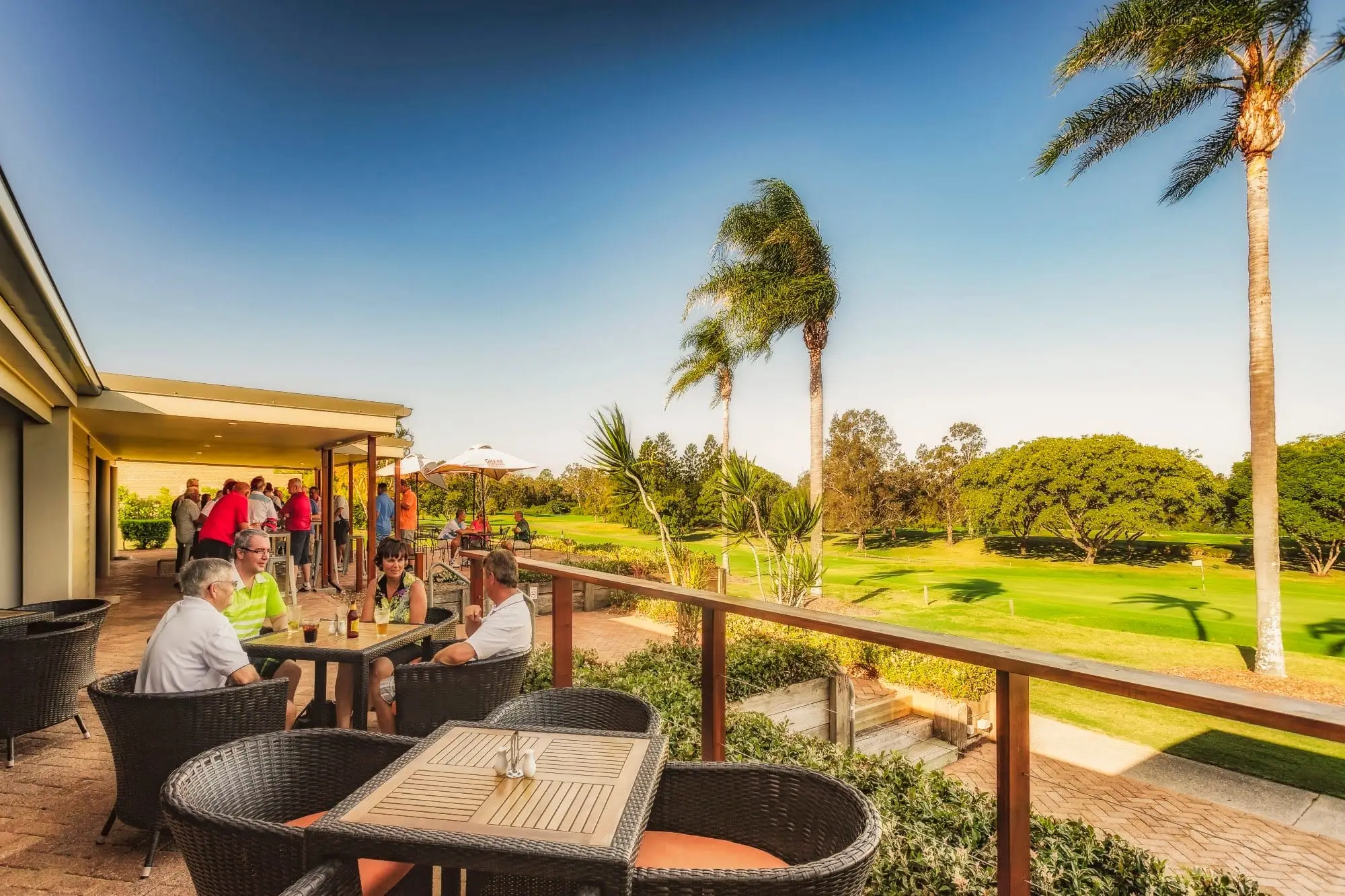 Clubhouse deck with golfers overlooking the course in evening sun