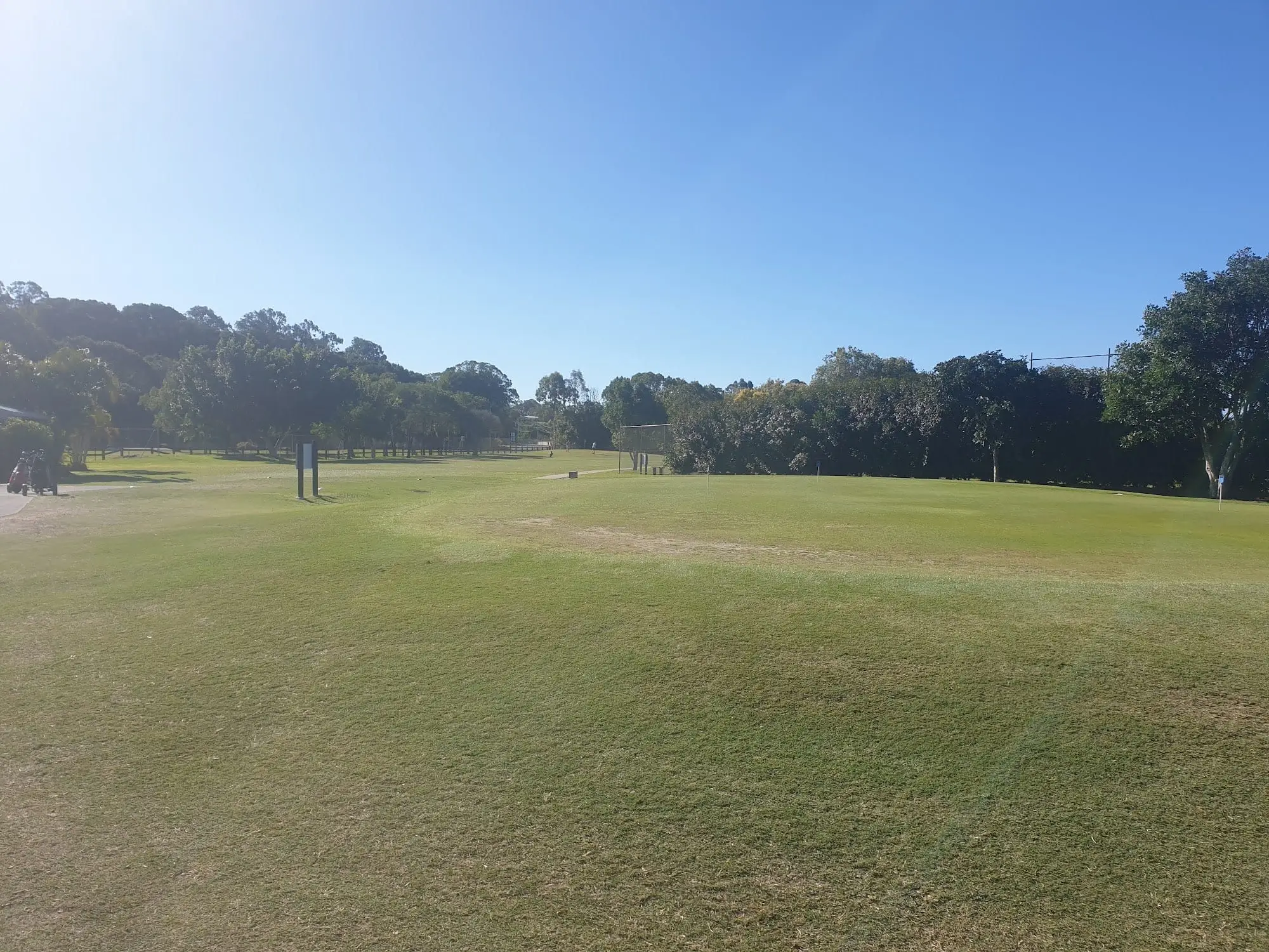 Open fairway under blue sky with trees beyond