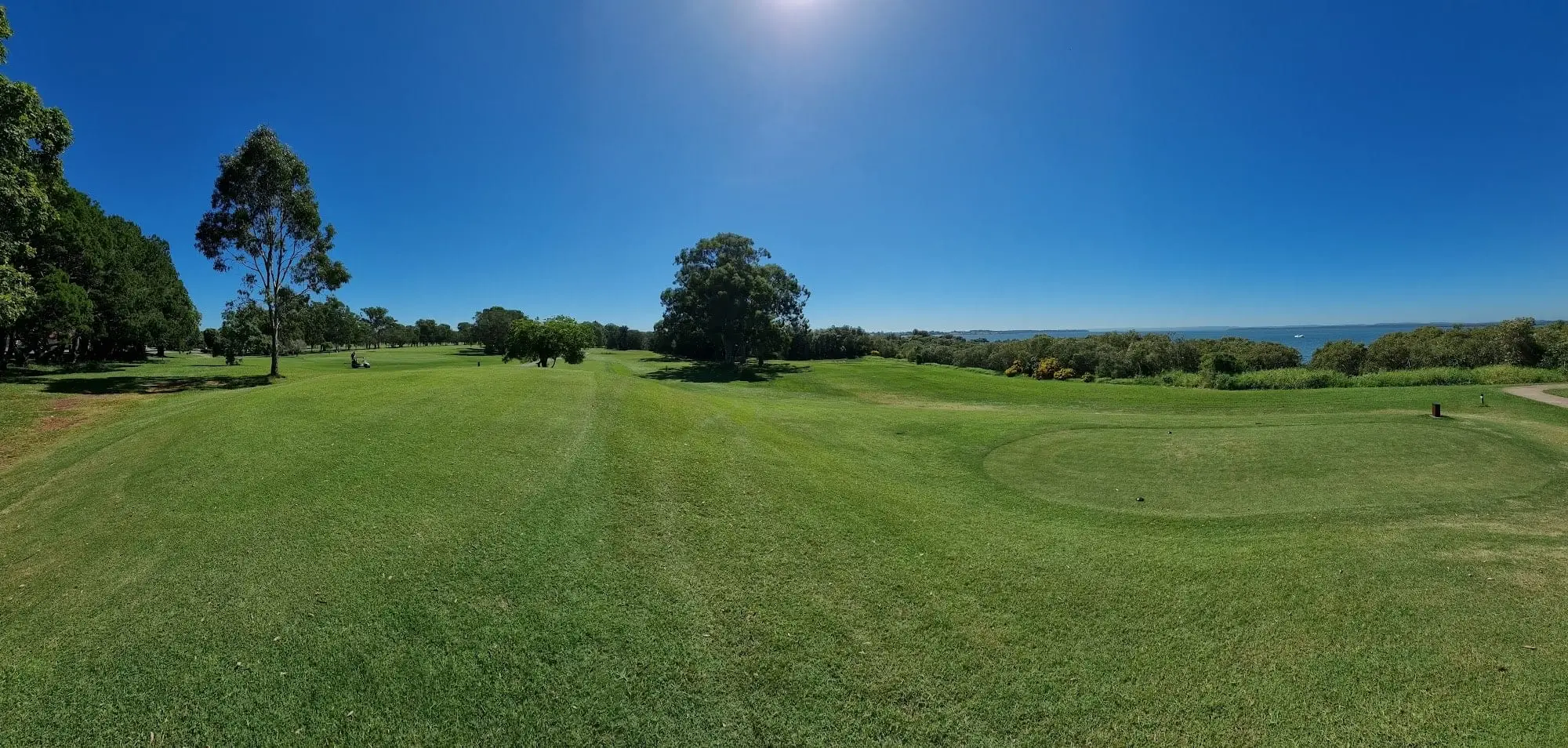 Wide fairway rolling toward the bay under a bright sky