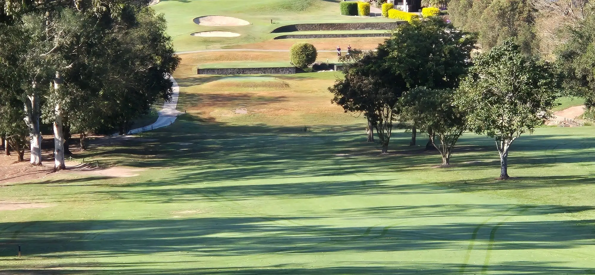 Fairway running downhill toward terraced bunkers and a distant green