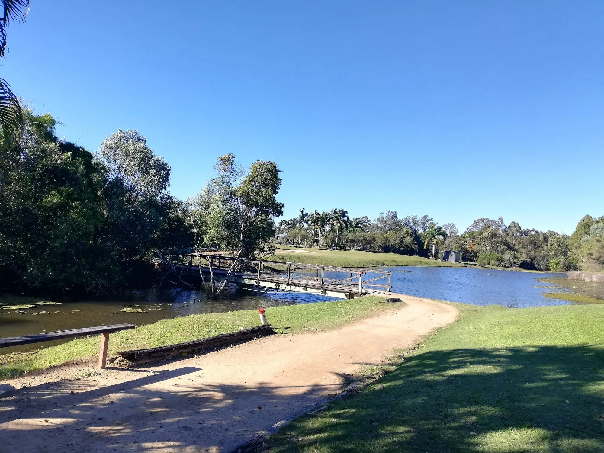 Footbridge and sandy path beside a lake on a clear day