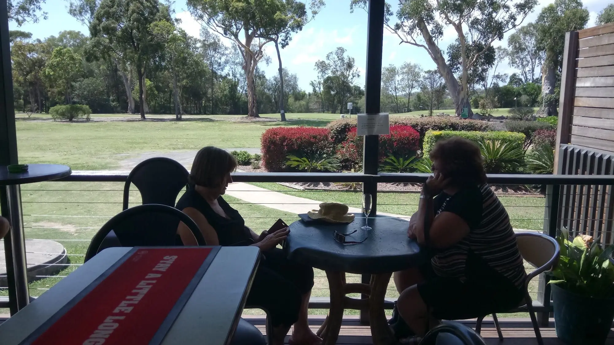 View over a fairway from the clubhouse verandah through trees