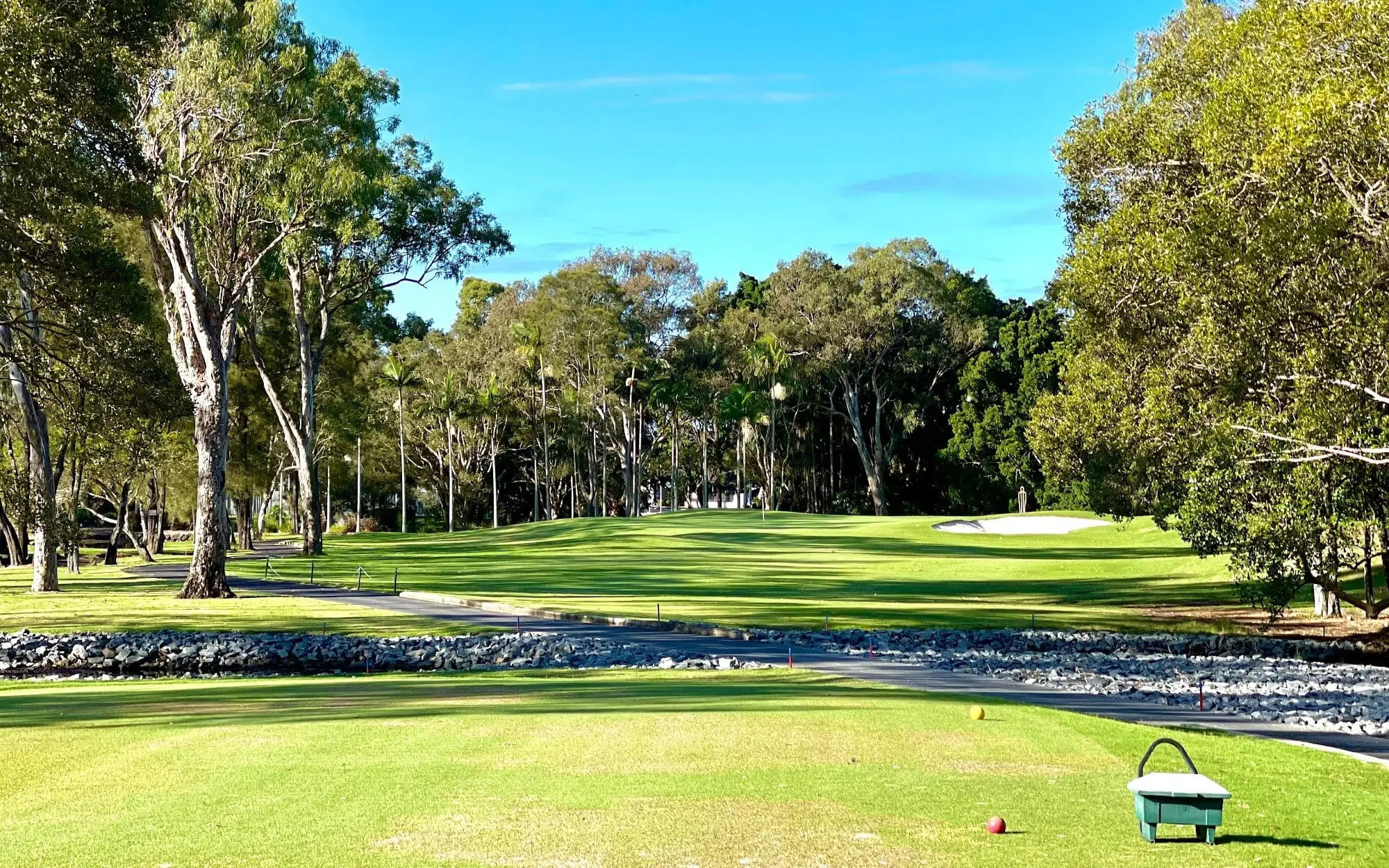 Tee view down a fairway beside a stone-lined creek